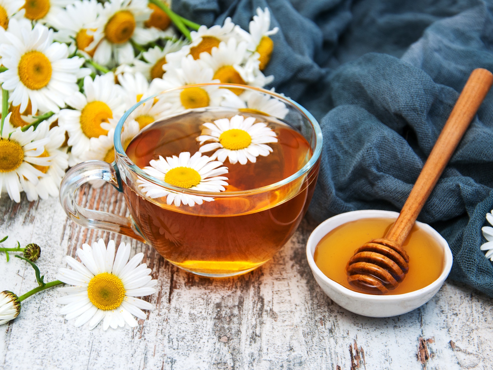 Чашка чая на столе с медом и букетом ромашек
