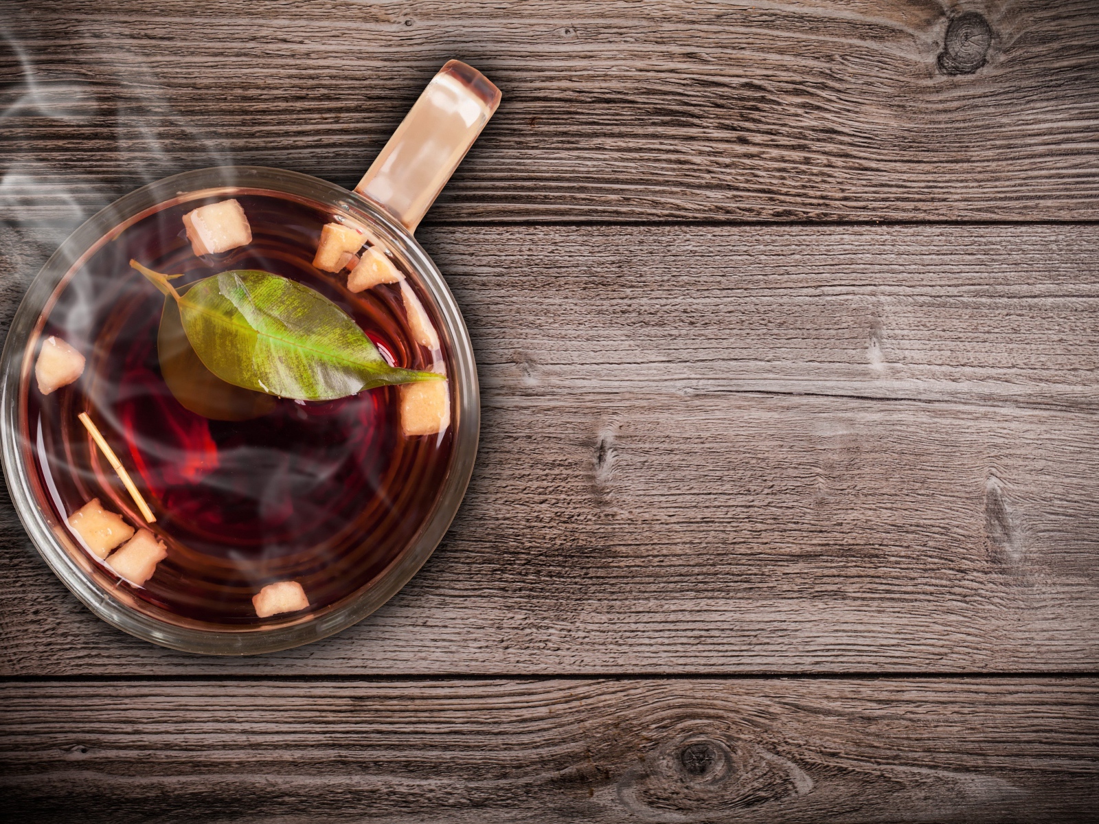 Стеклянная чашка горячего чая на деревянном столе