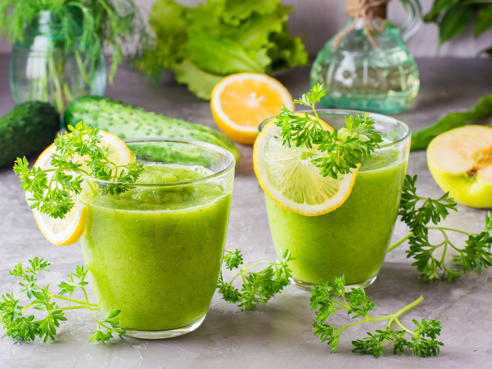 Зеленый смузи в стаканах с кусочками лимона и петрушкой