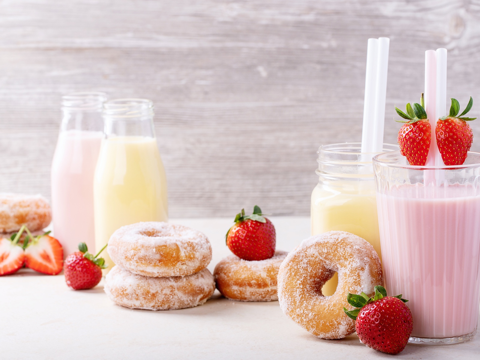 Молочные коктейли на столе с клубникой и пончиками