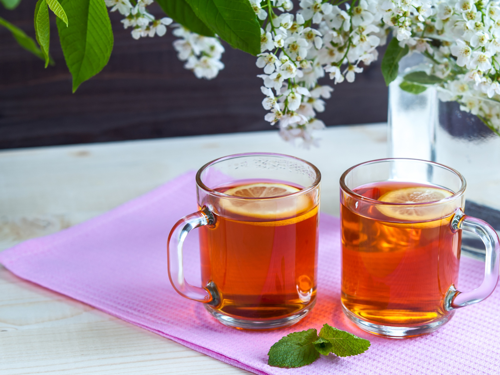 Две чашки чая с лимоном на столе с цветами 