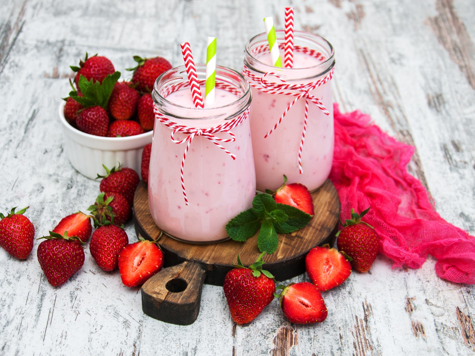 Две банки смузи стоят на доске на столе с клубникой