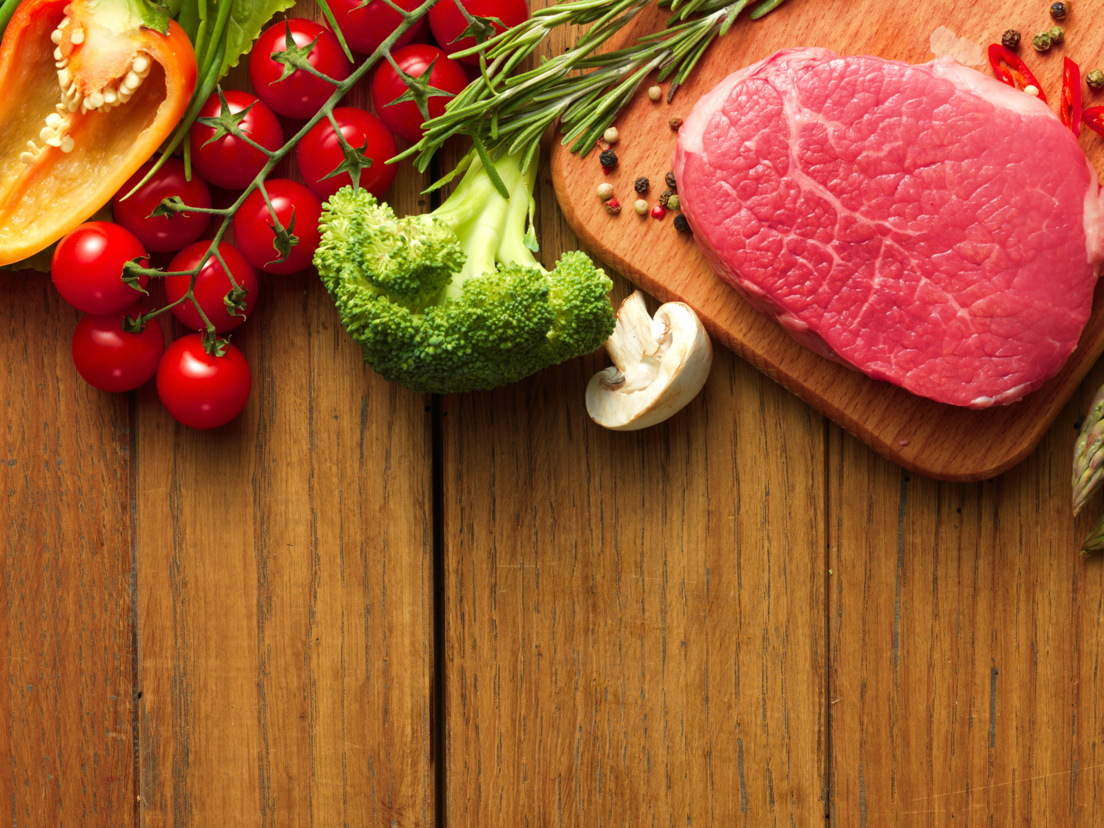 Кусок свежего мяса на столе с овощами и зеленью 