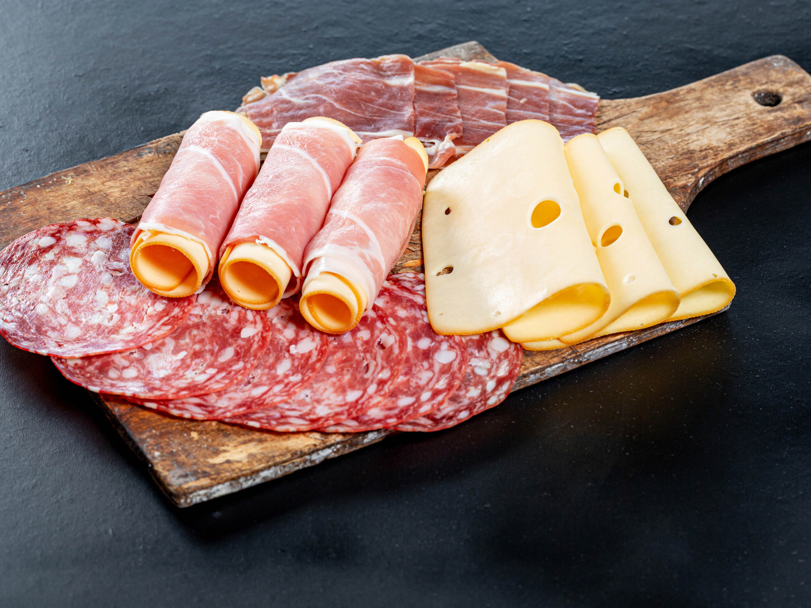 Ветчина на доске с колбасой и твердым сыром