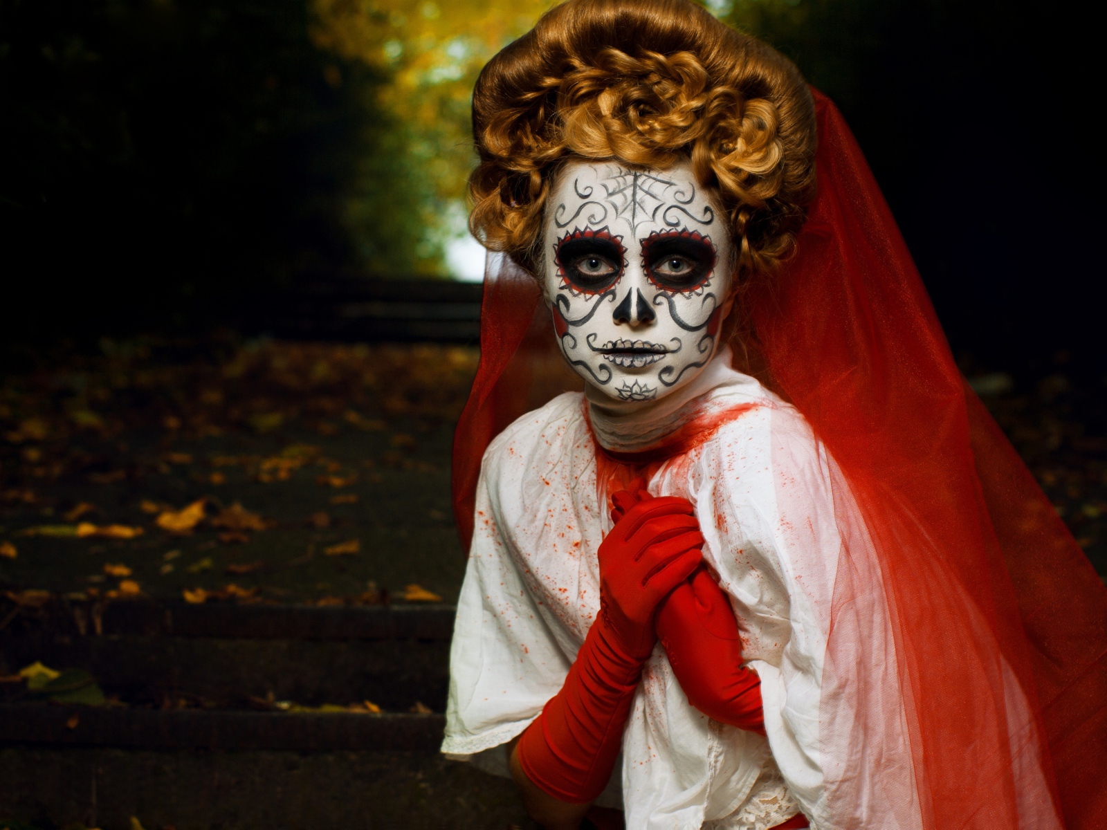 Девушка с маской на лице и красной фатой на праздник Хэллоуин 