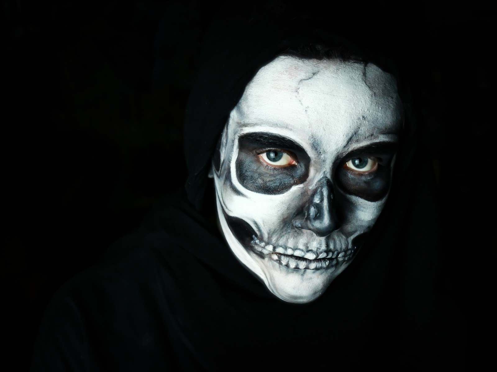 Девушка с маской с грима на лице на черном фоне
