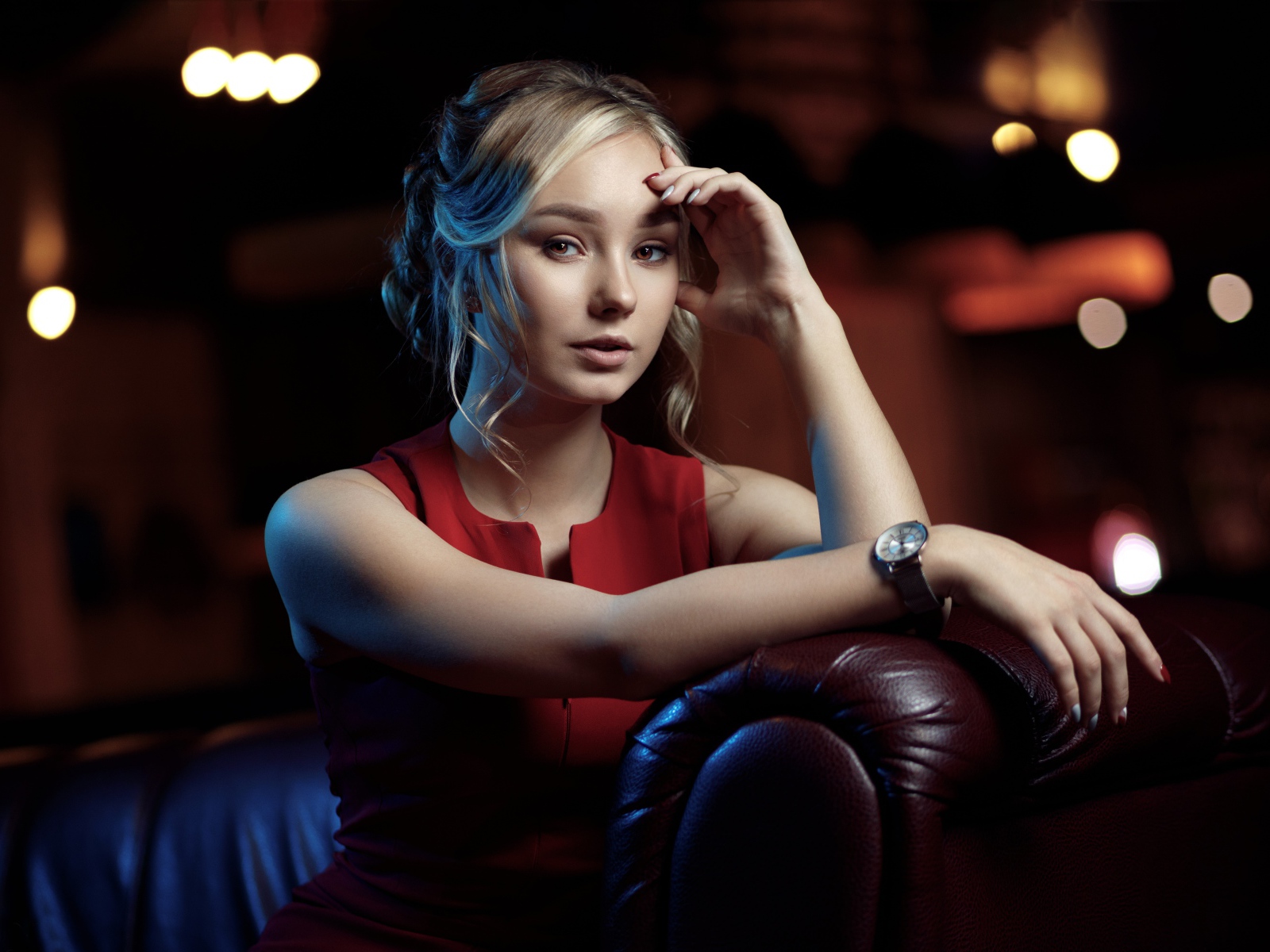 Красивая девушка с часами на руке сидит в кресле