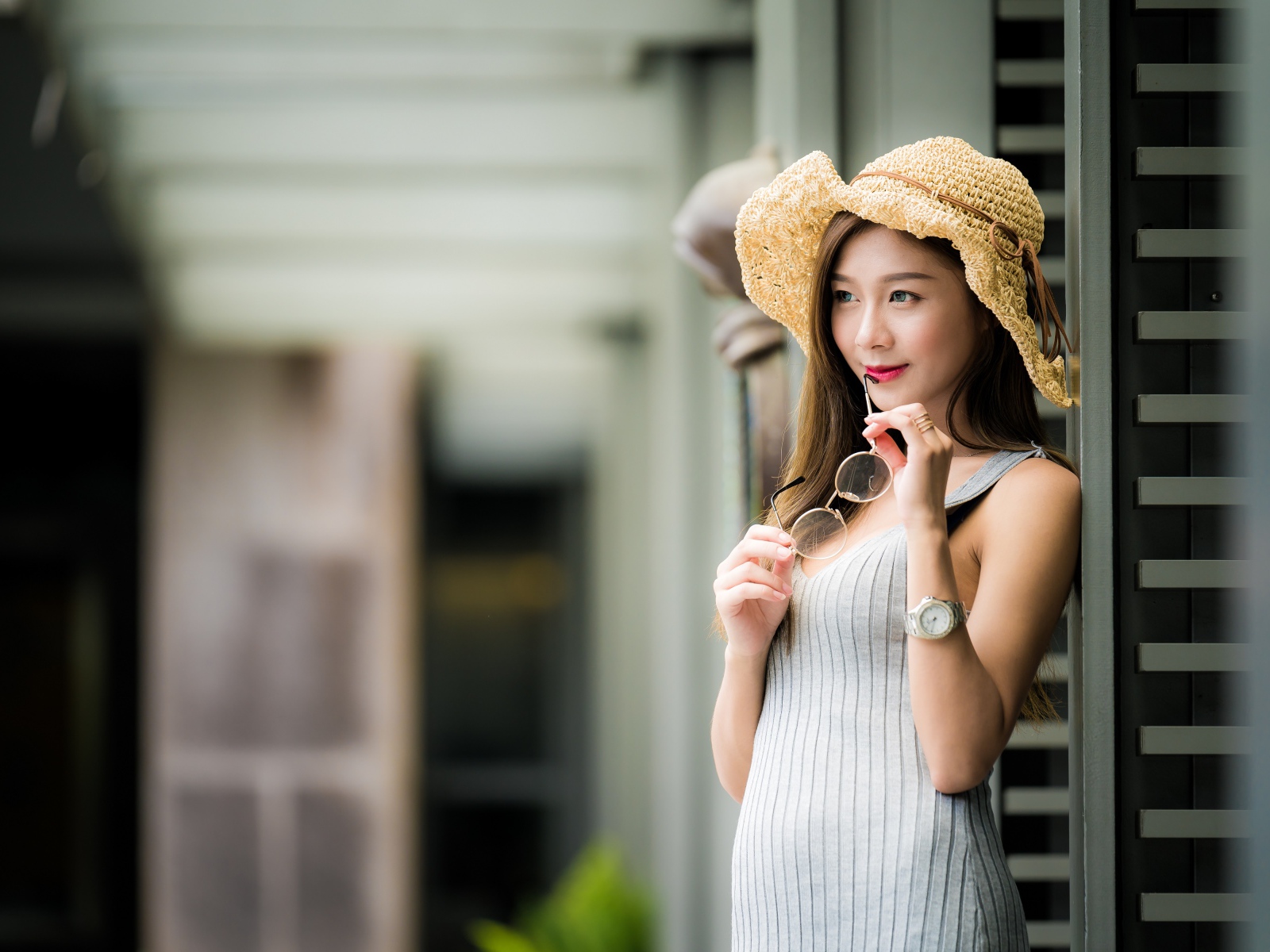 Девушка азиатка в шляпке с очками в руках 