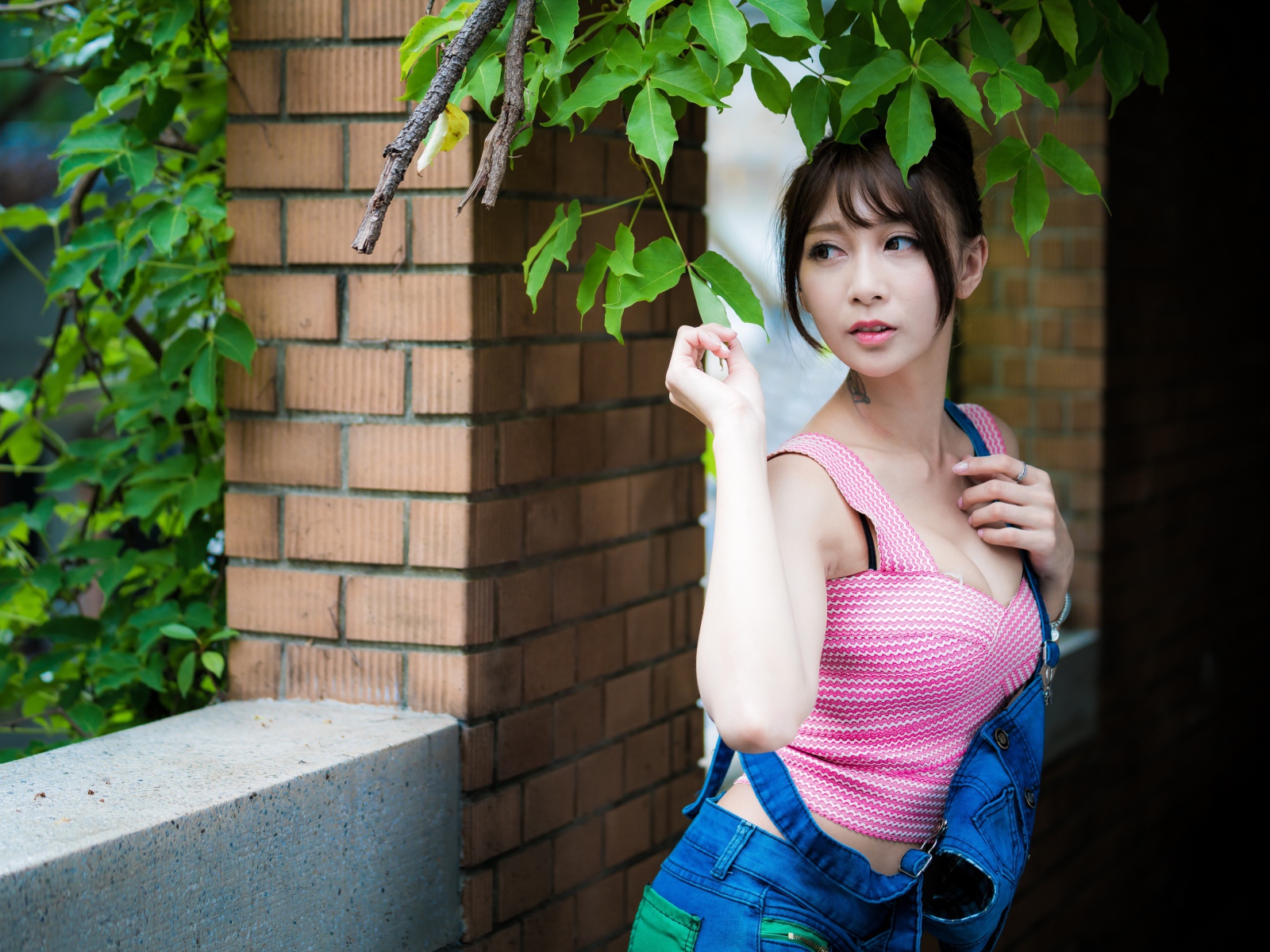 Молодая девушка азиатка у стены с зелеными листьями