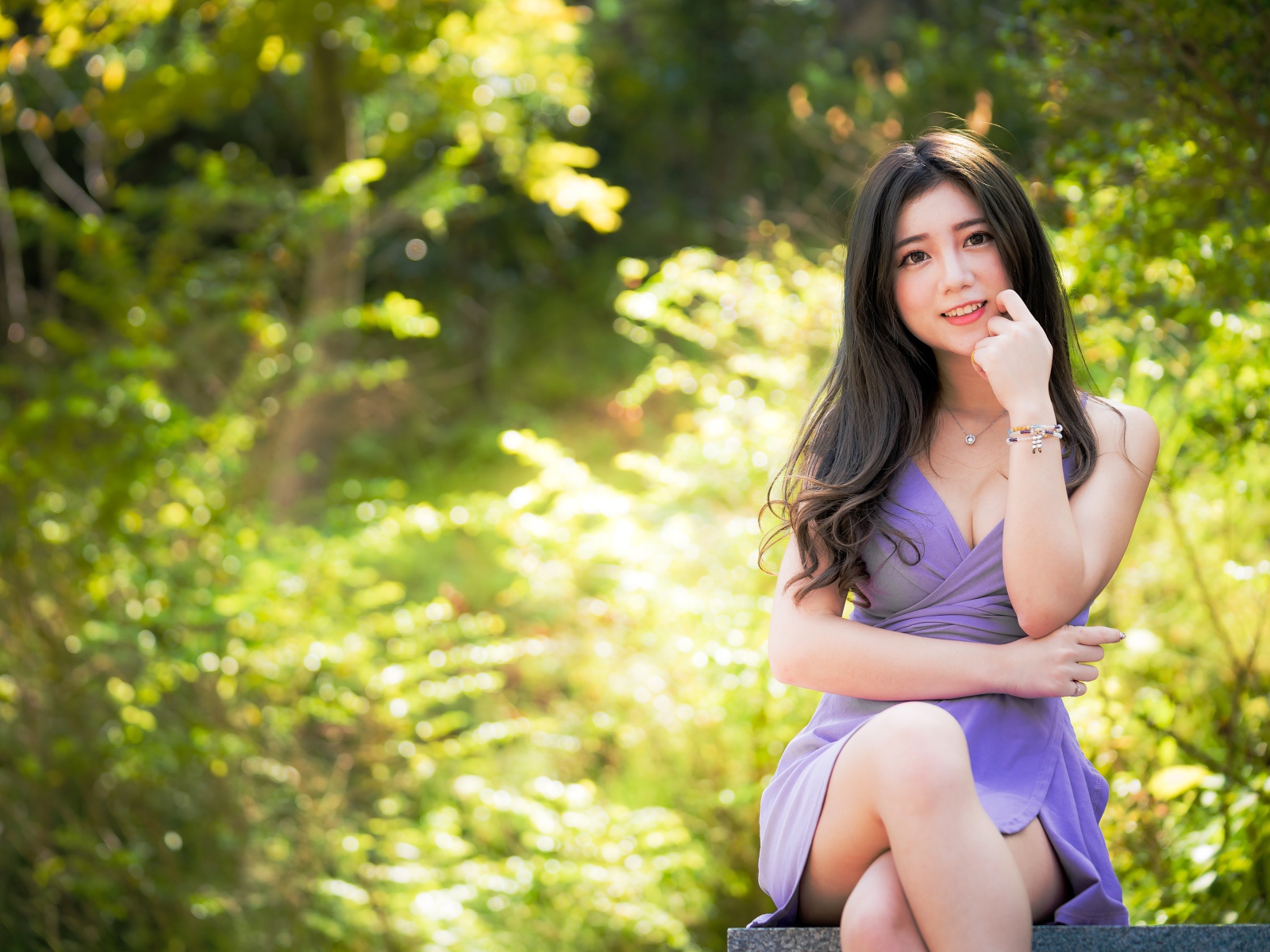 Молодая девушка азиатка сидит на лавке в парке