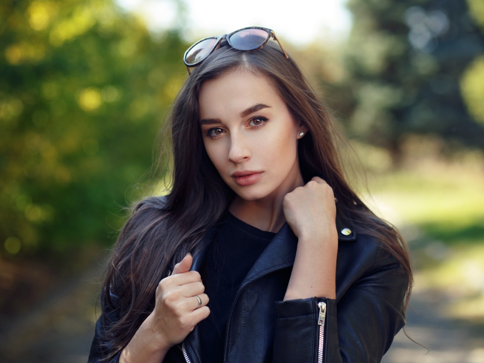 Красивая девушка в черной куртке с очками на голове