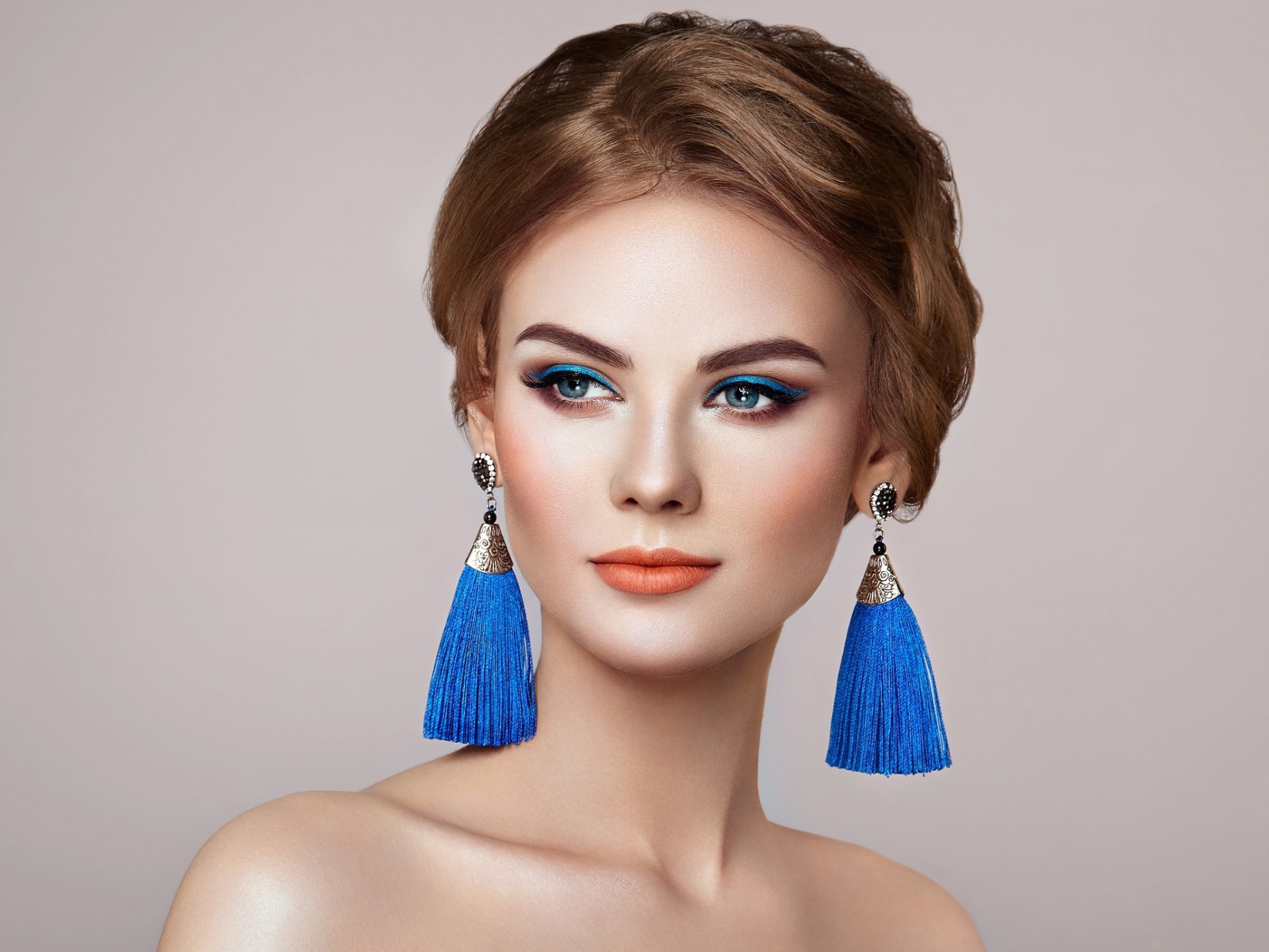 Красивая девушка с синими сережками на сером фоне
