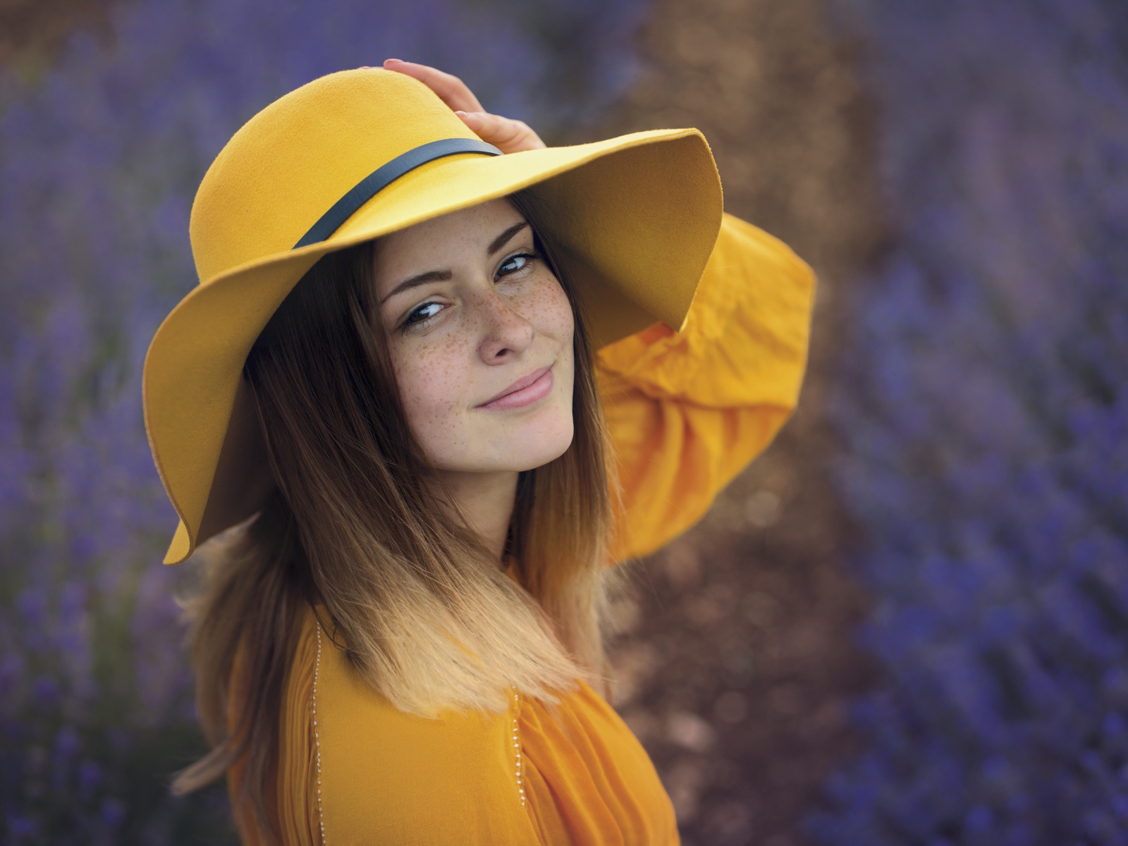 Красивая девушка с веснушками на лице в желтой шляпе
