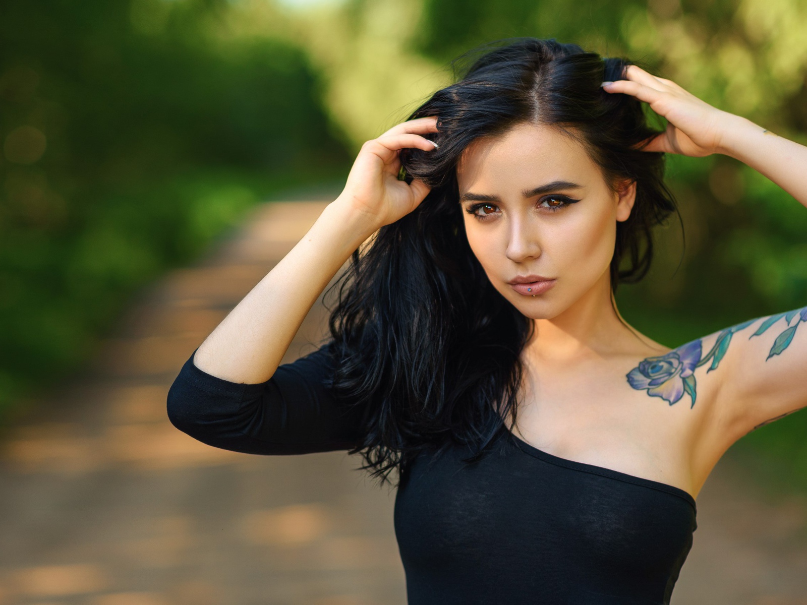 Красивая молодая девушка в черном с татуировкой на руке