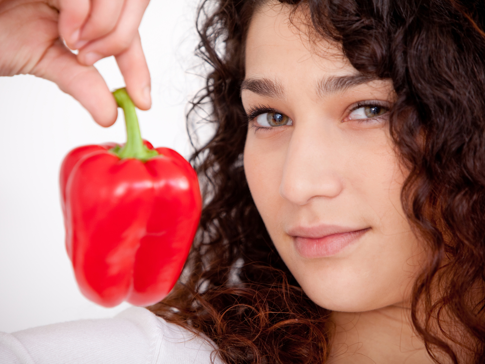 Лицо девушки с красным сладким перцем в руке крупным планом