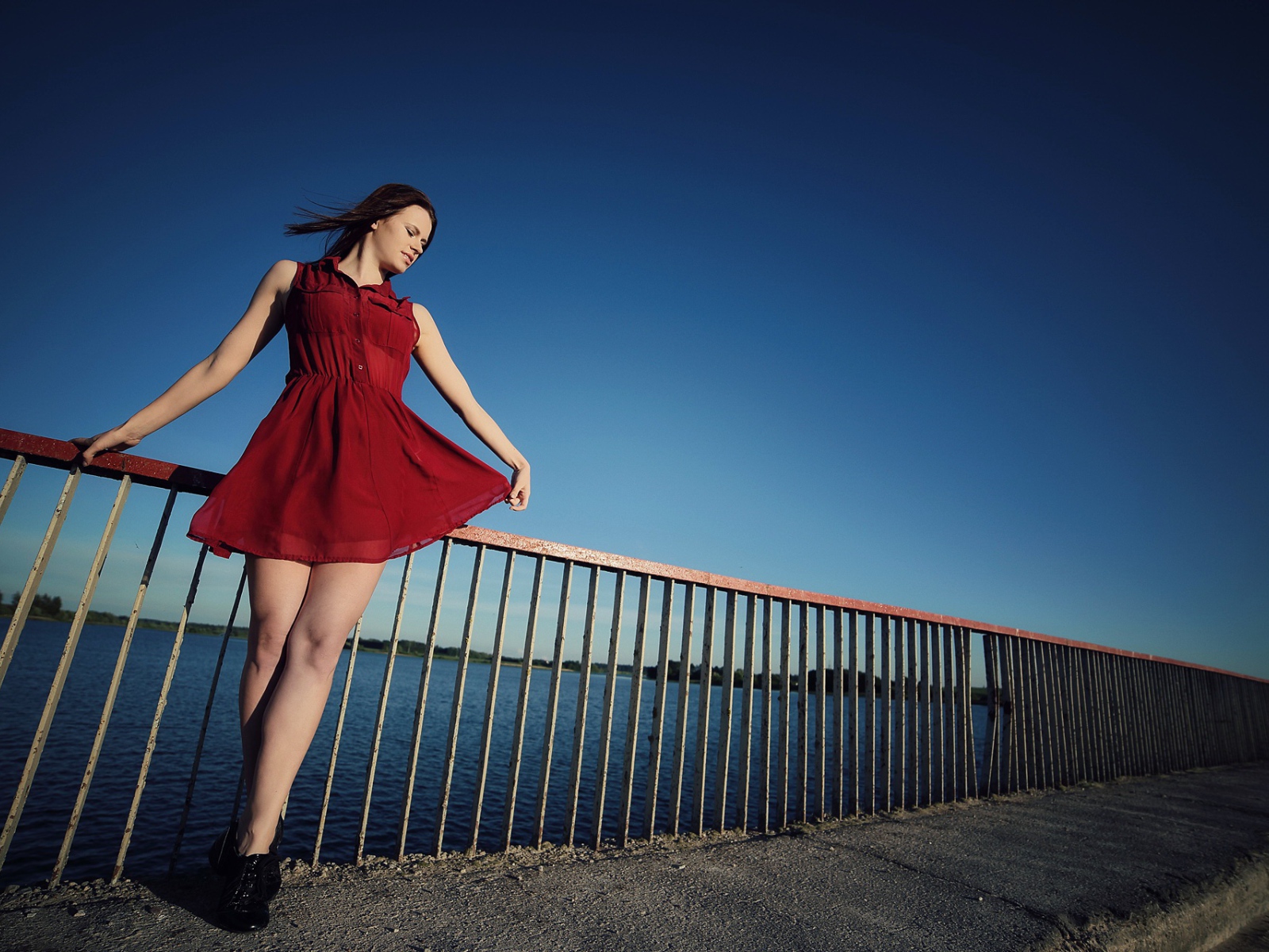 Девушка в коротком красном платье на мосту 
