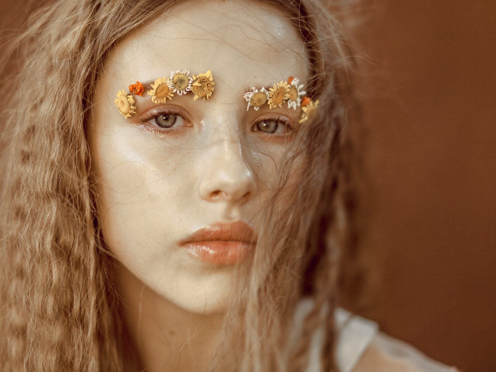 Девушка с цветами на бровях крупным планом