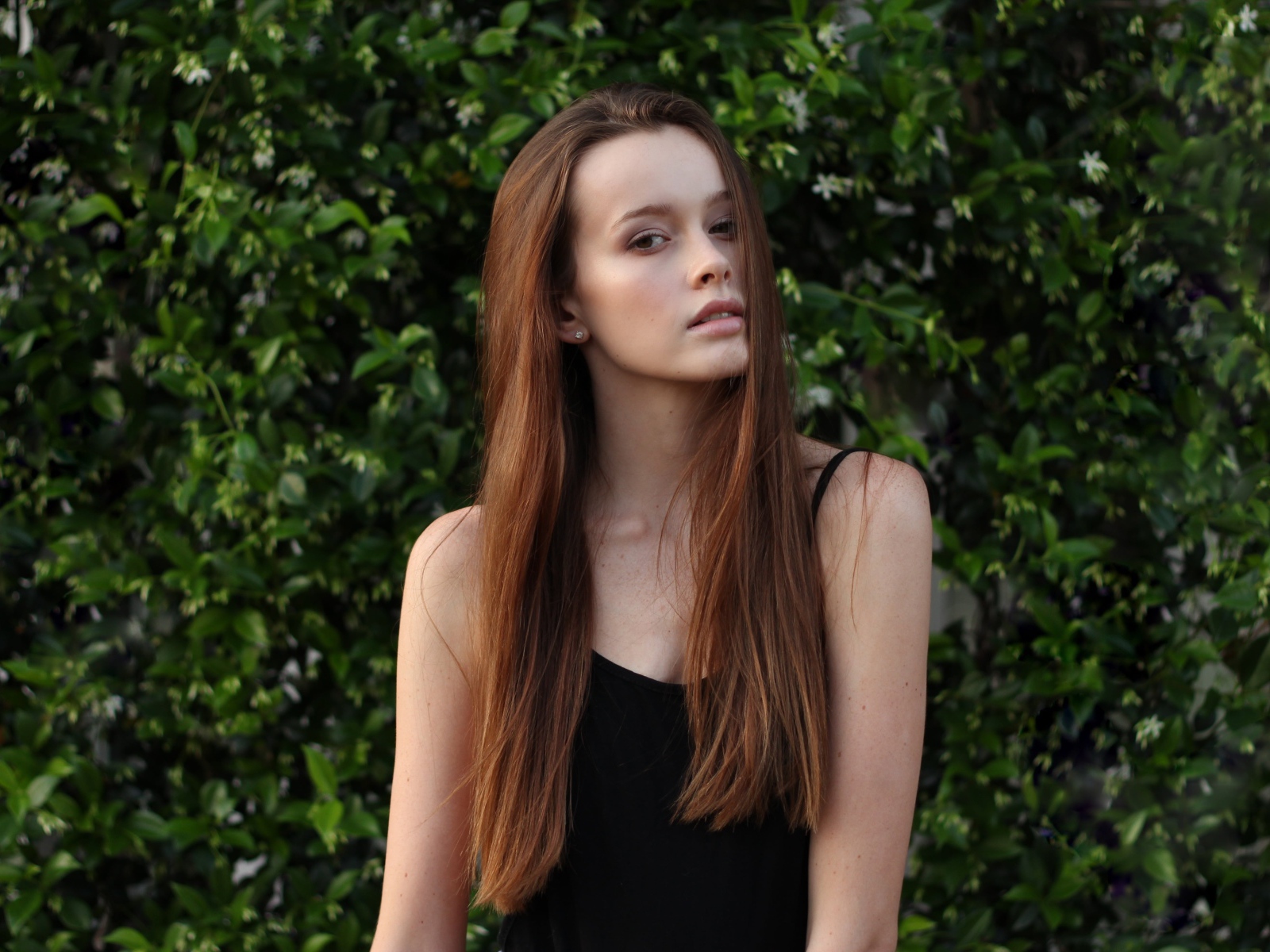 Длинноволосая шатенка на фоне зеленых зарослей