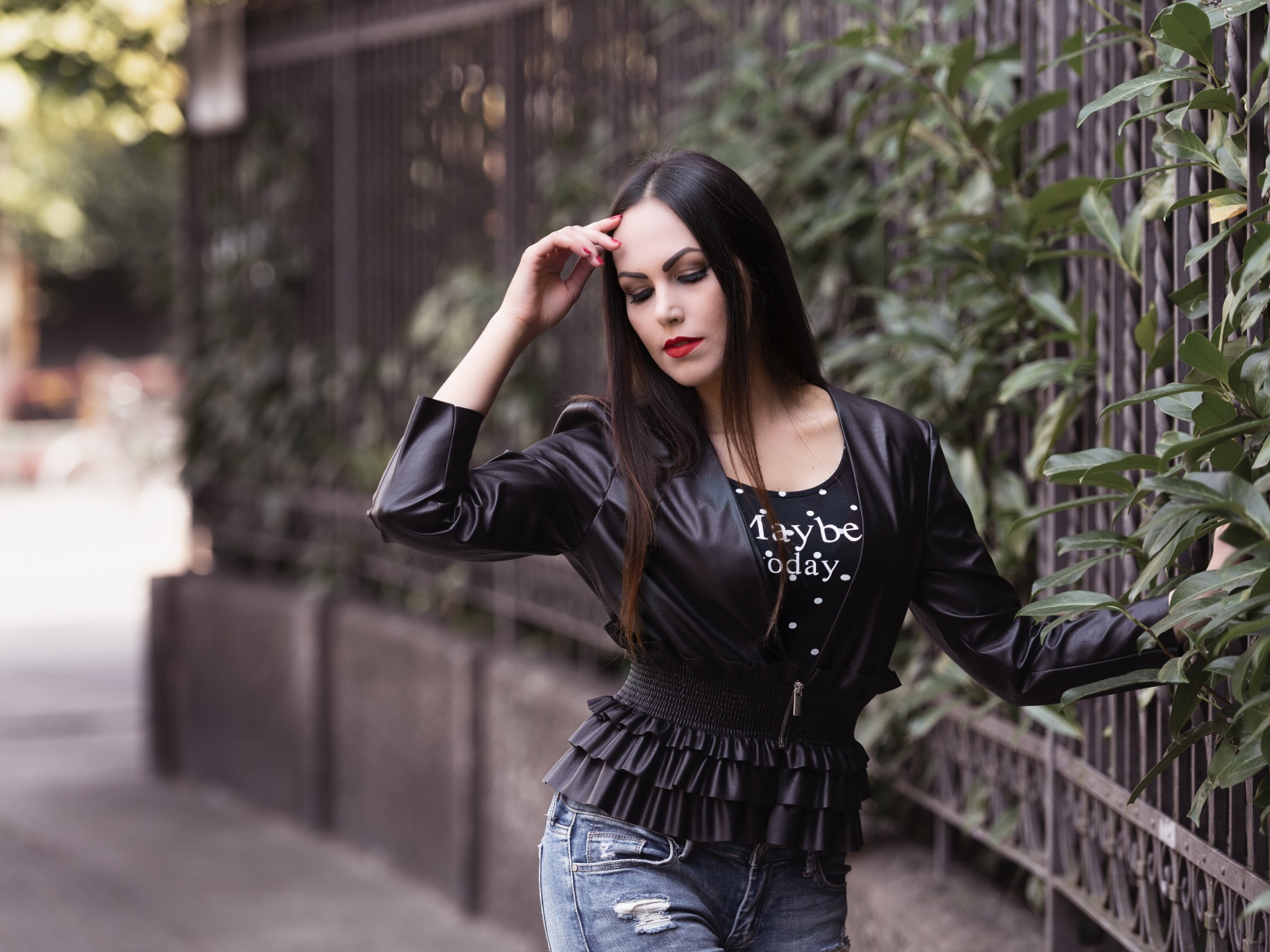 Длинноволосая брюнетка в черной куртке у забора