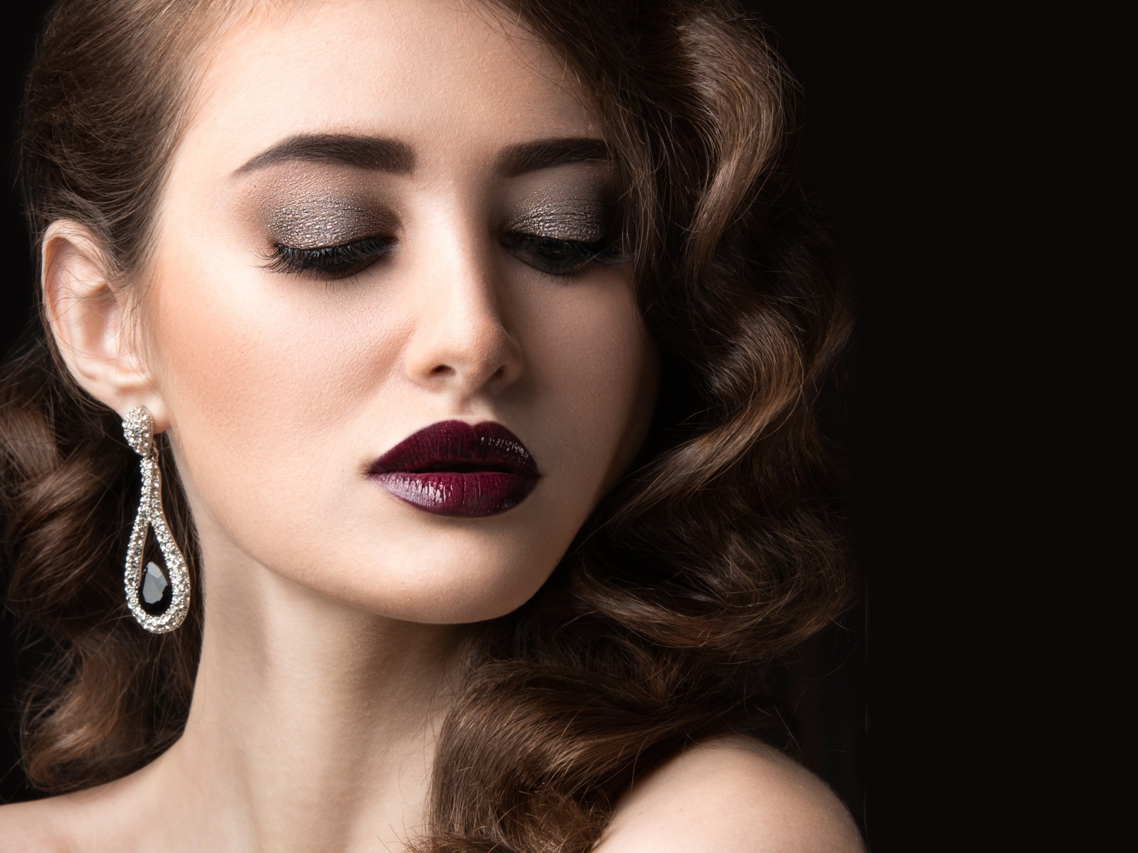 Длинноволосая девушка с ярким макияжем на черном фоне