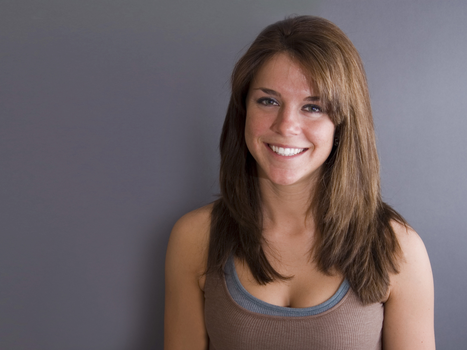 Улыбающаяся милая девушка у серой стены