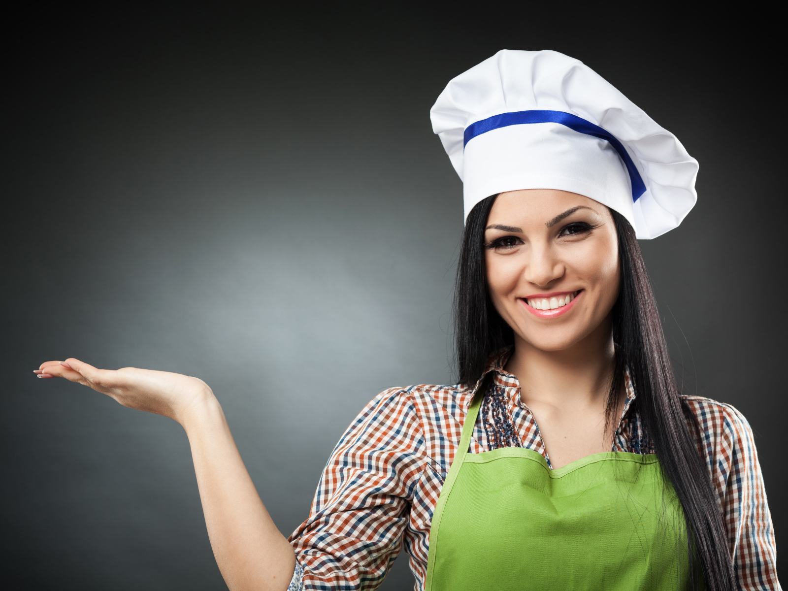 Улыбающаяся девушка в поварском колпаке на сером фоне