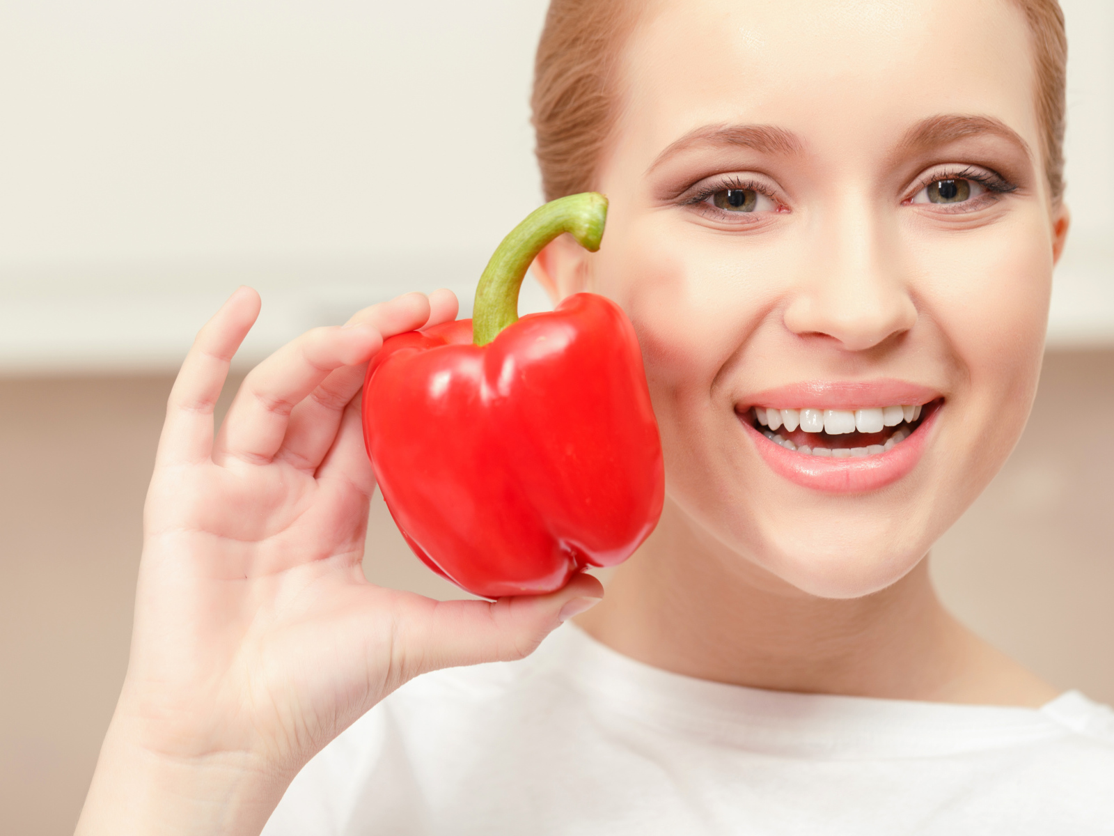 Улыбающаяся девушка с красным сладким перцем в руке