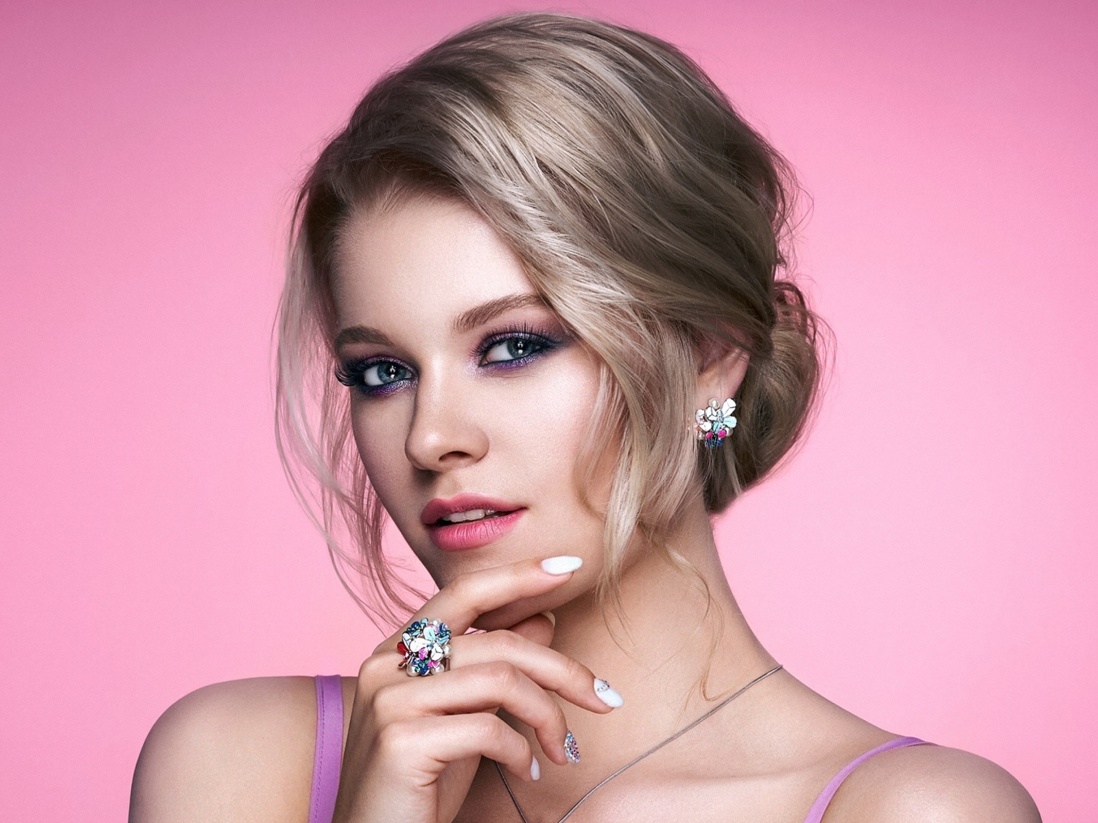 Стильная блондинка с прической на розовом фоне