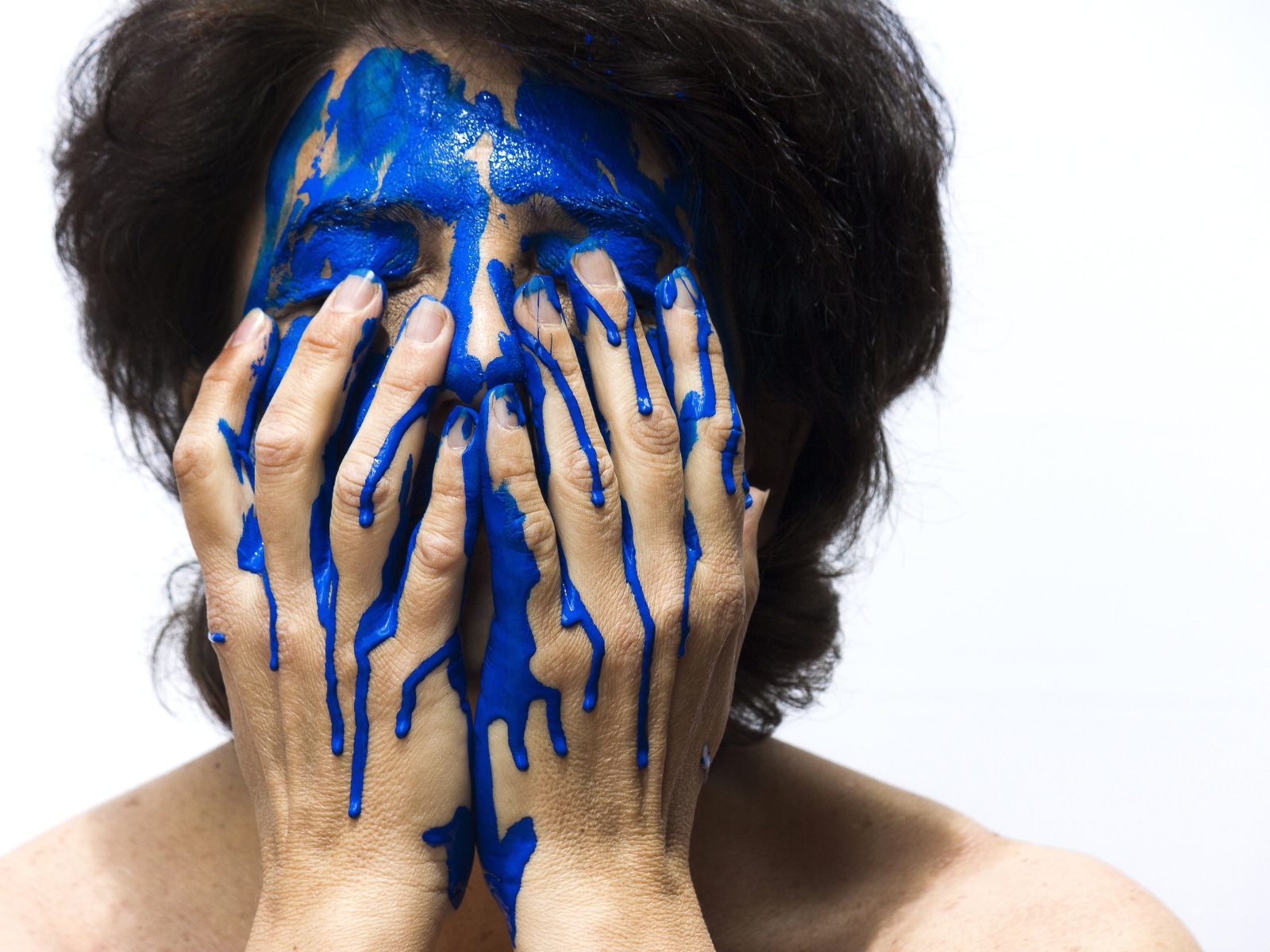 Лицо и руки женщины в синей краске