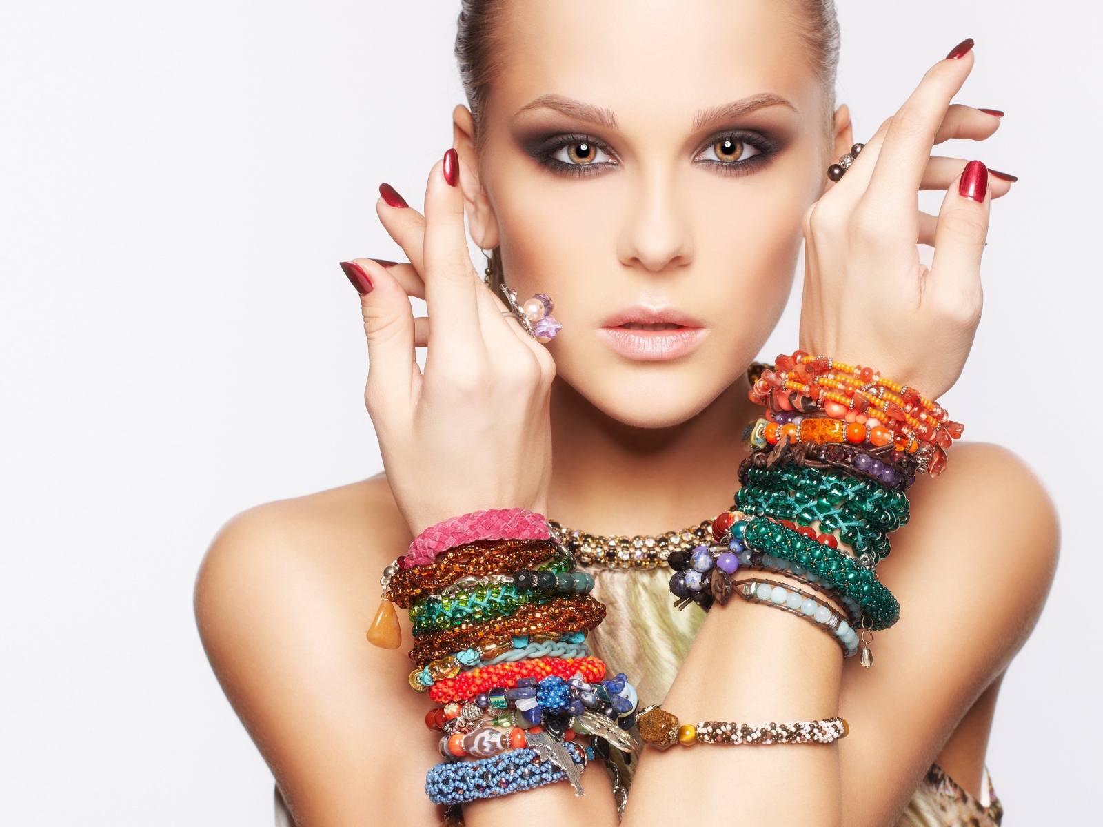 Молодая кареглазая девушка с браслетами на руках на белом фоне