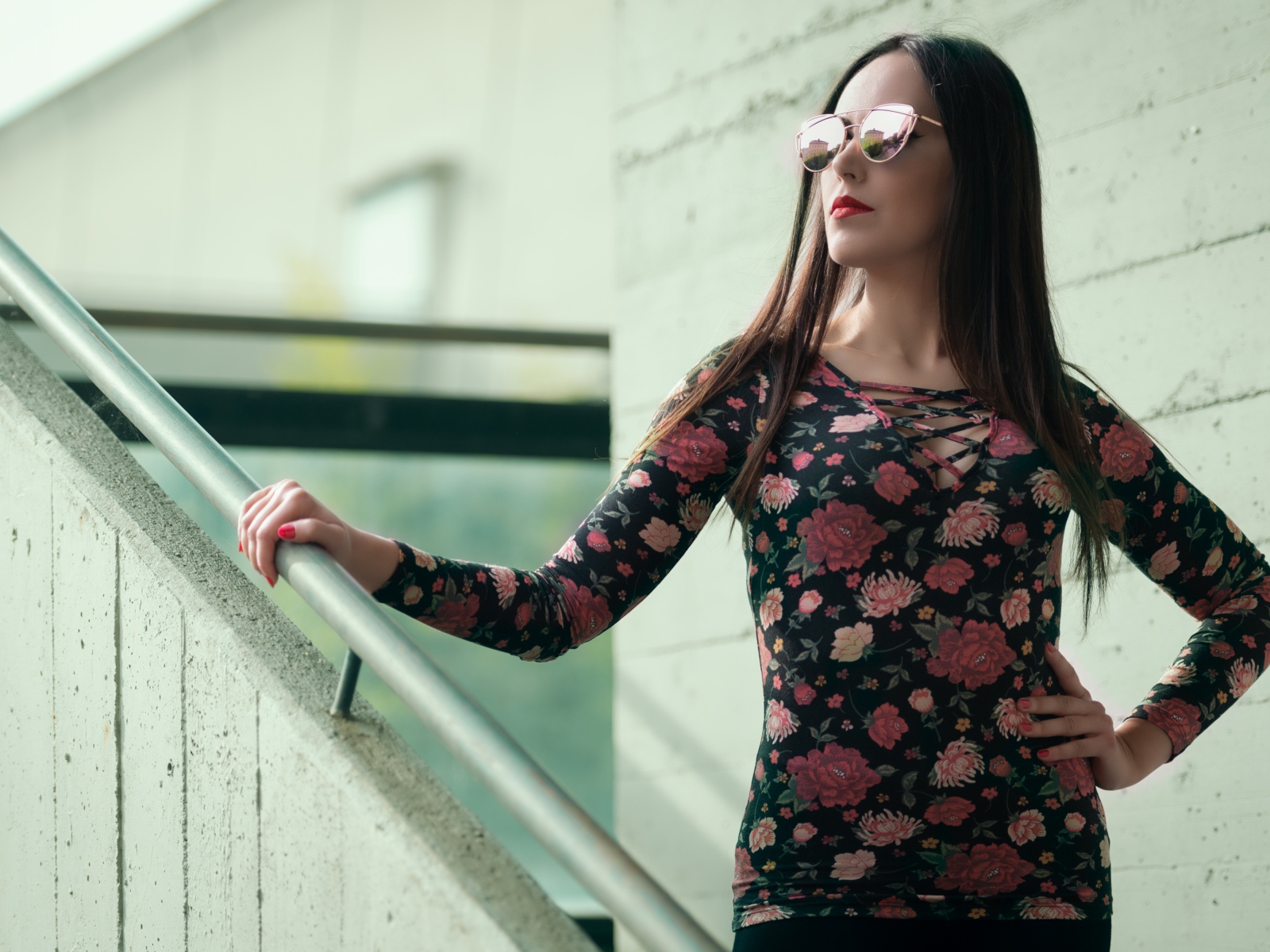 Молодая девушка в солнечных очках стоит на ступеньках