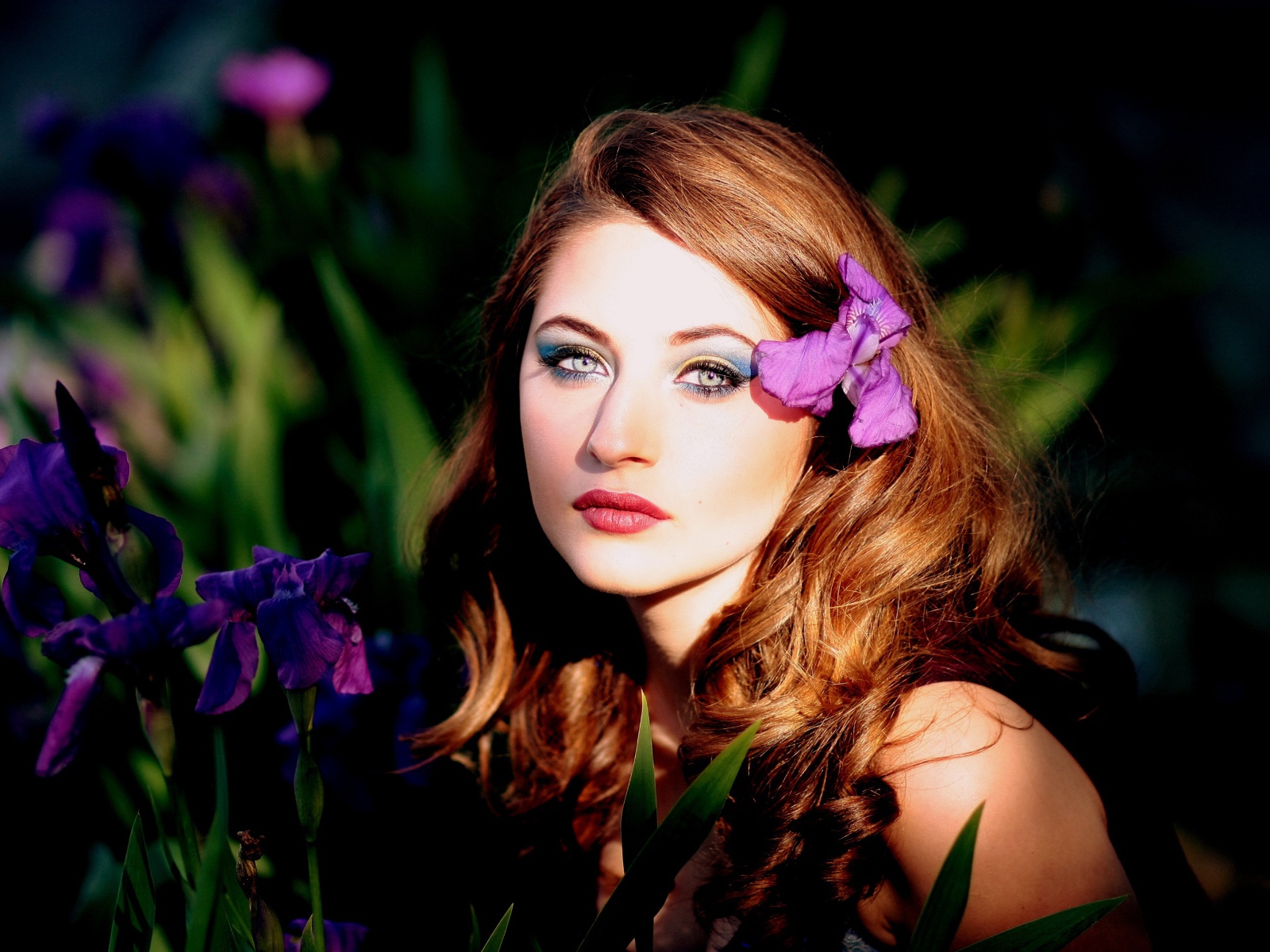 Молодая девушка с фиолетовым цветком ириса в волосах