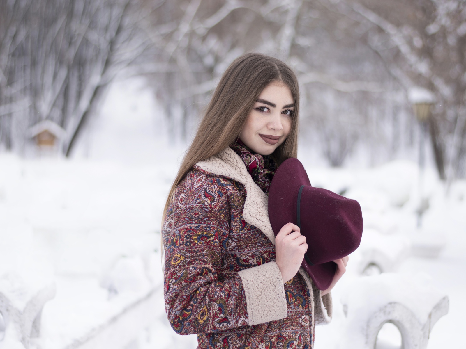 Молодая длинноволосая девушка шатенка с шляпой в руках зимой