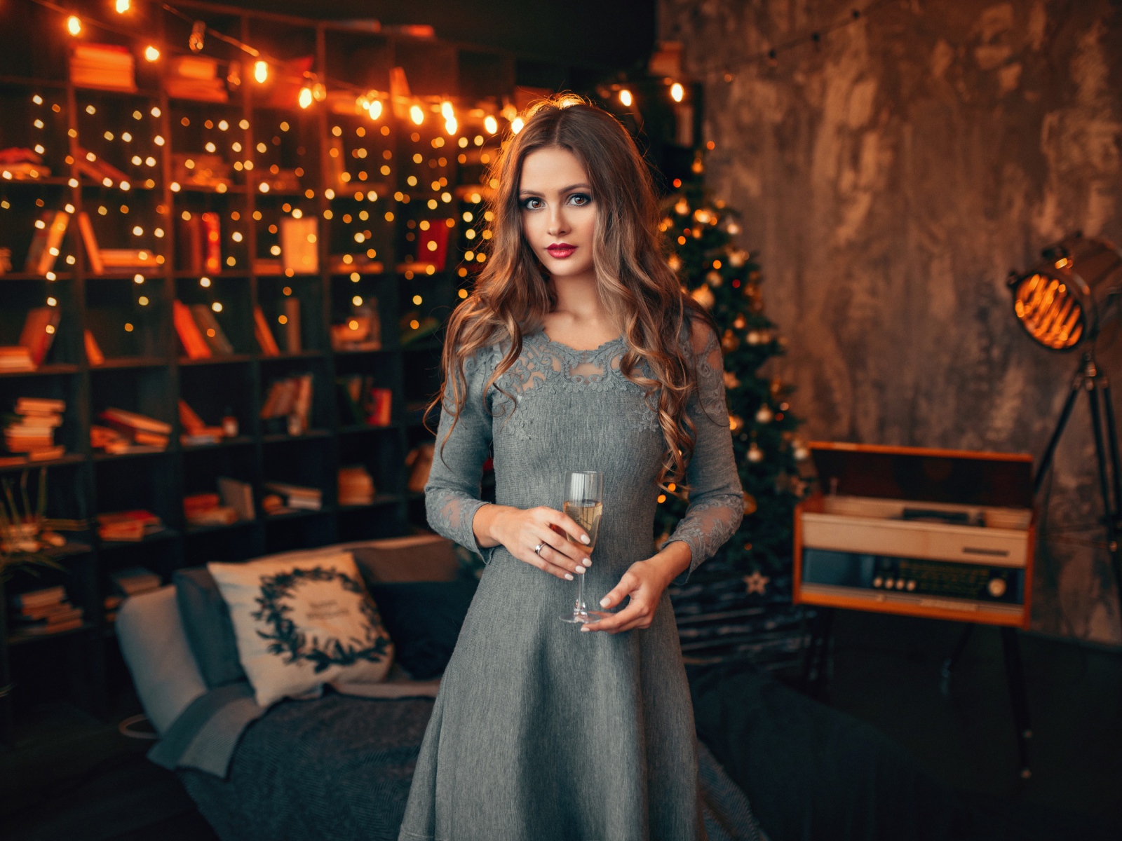 Красивая девушка с бокалом шампанского в комнате украшенной гирляндой