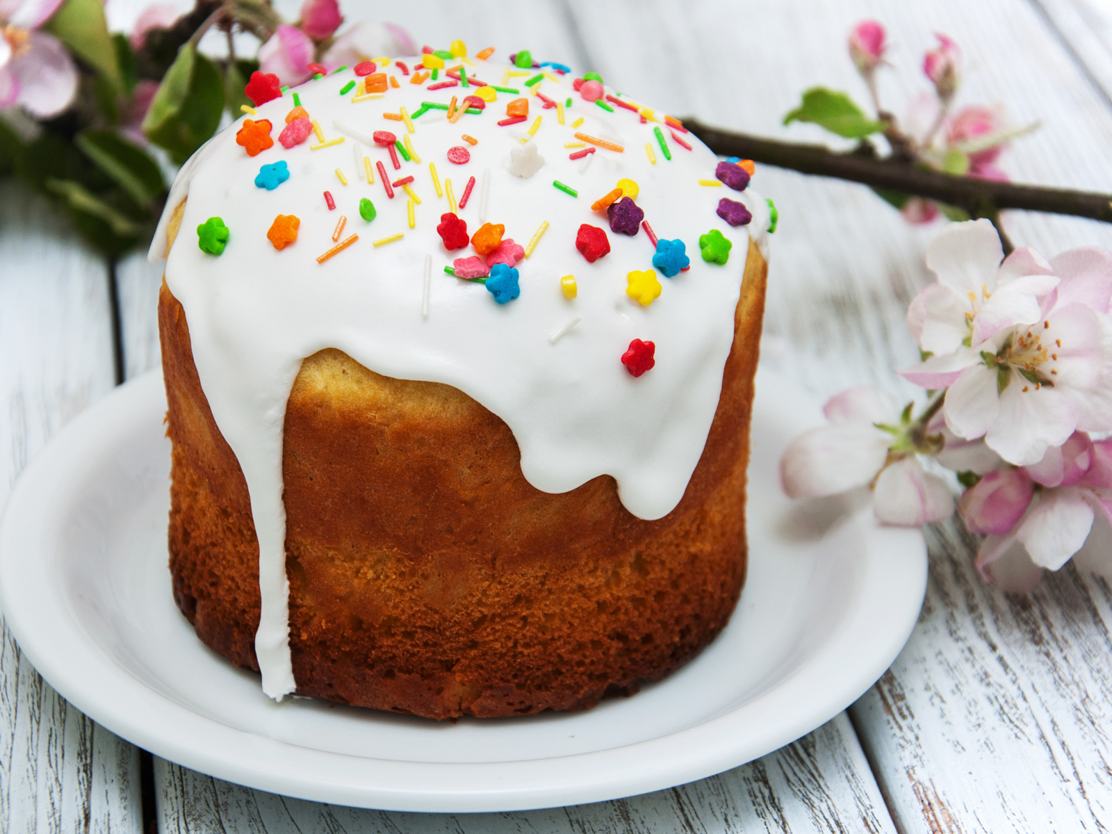 Красивый кулич с белой глазурью на столе с веткой яблони на Великий праздник Пасха