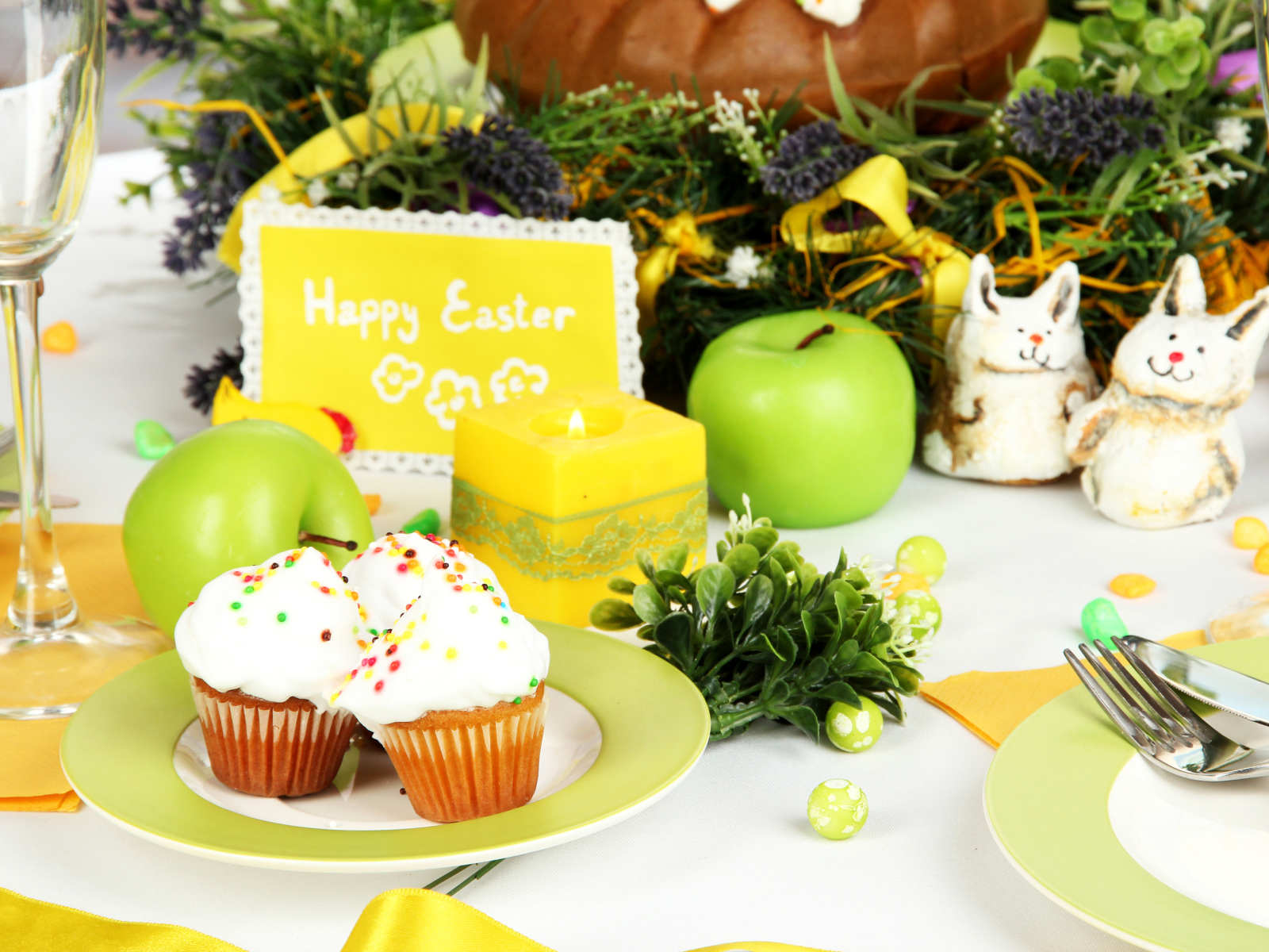 Накрытый пасхальный стол с кексами и зажженной свечой 