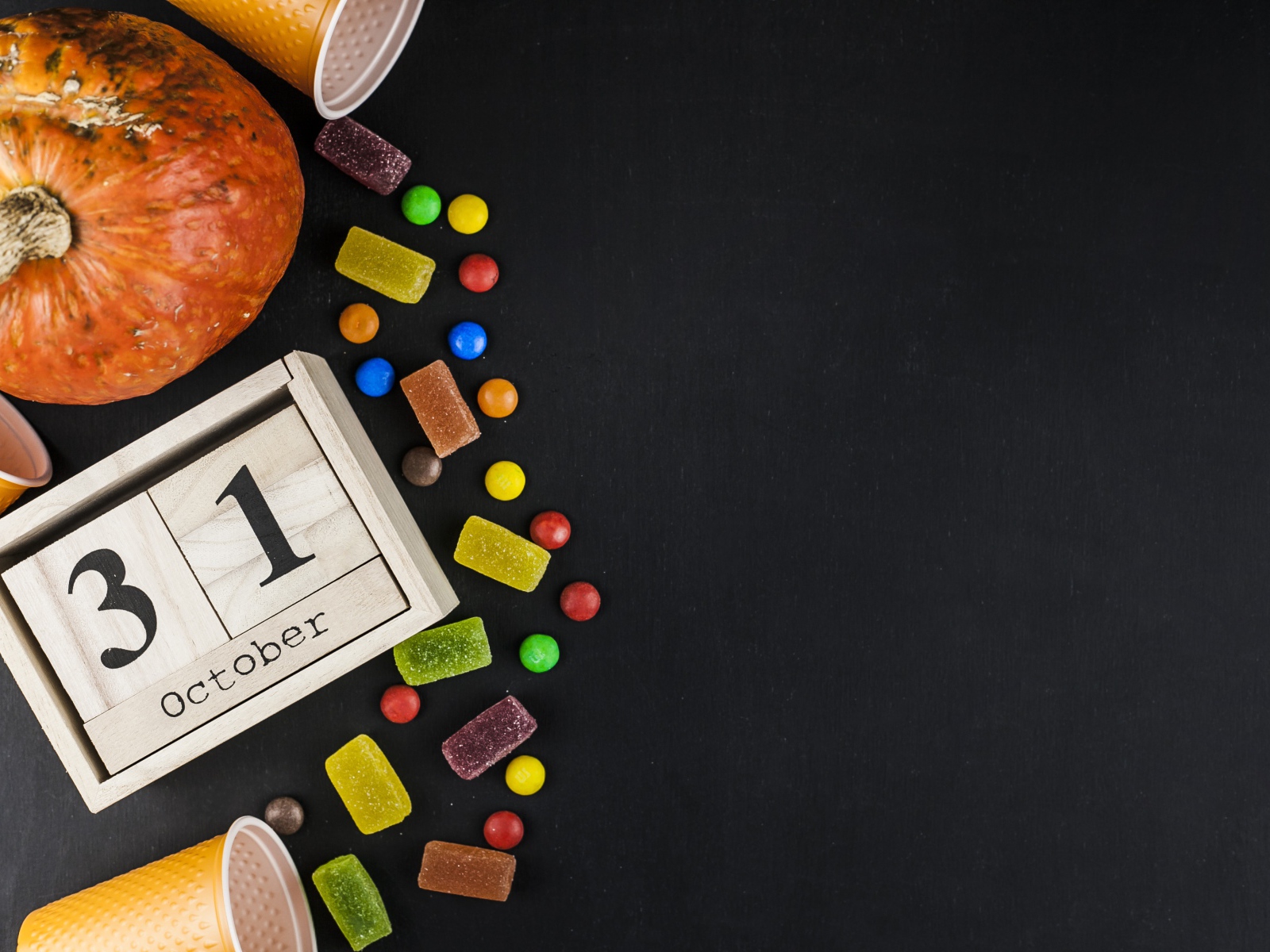 Конфеты, тыква и календарь на сером фоне на Хэллоуин