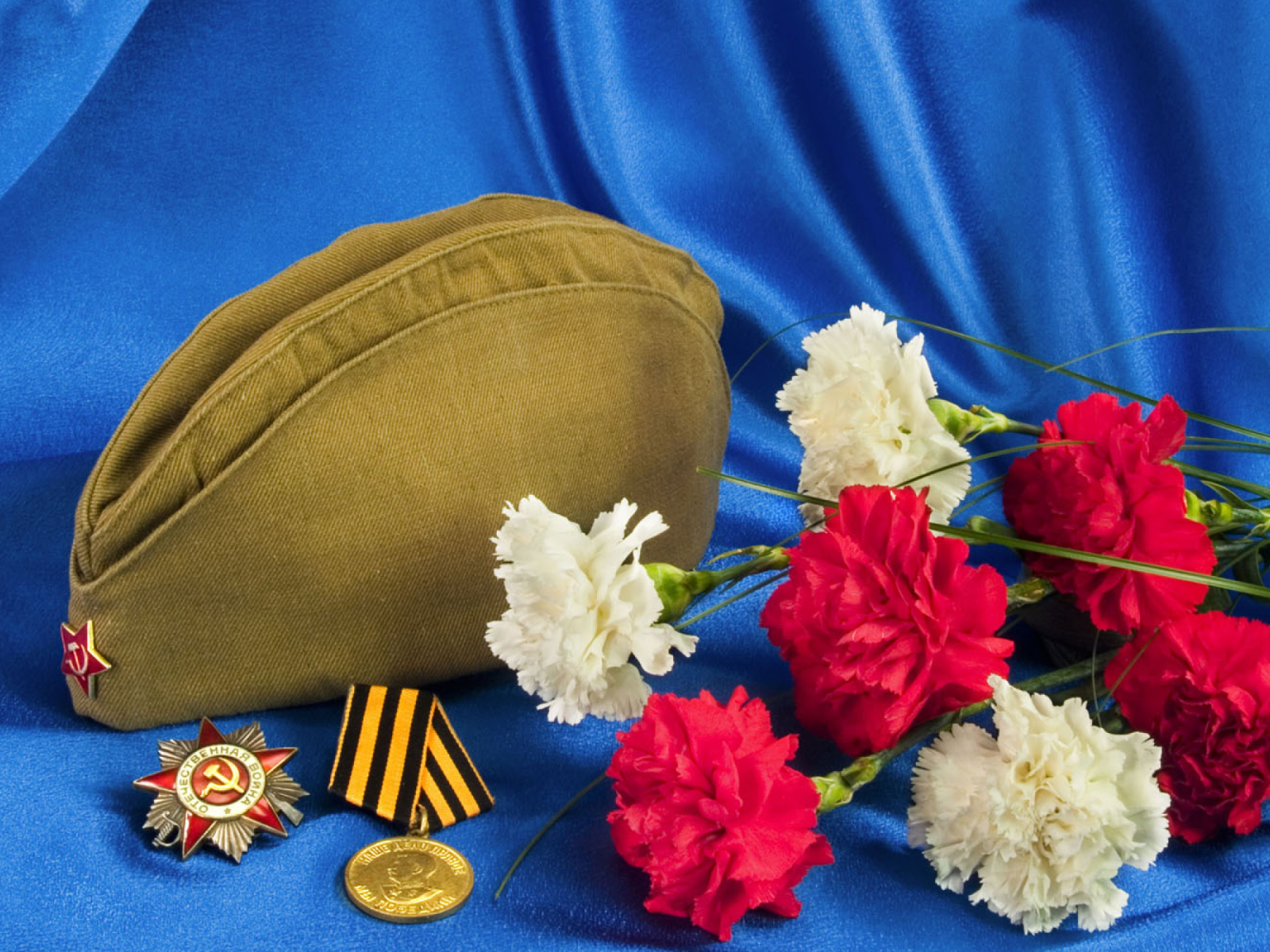 Букет гвоздик, пилотка, орден отечественной войны, и медаль на синем фоне 