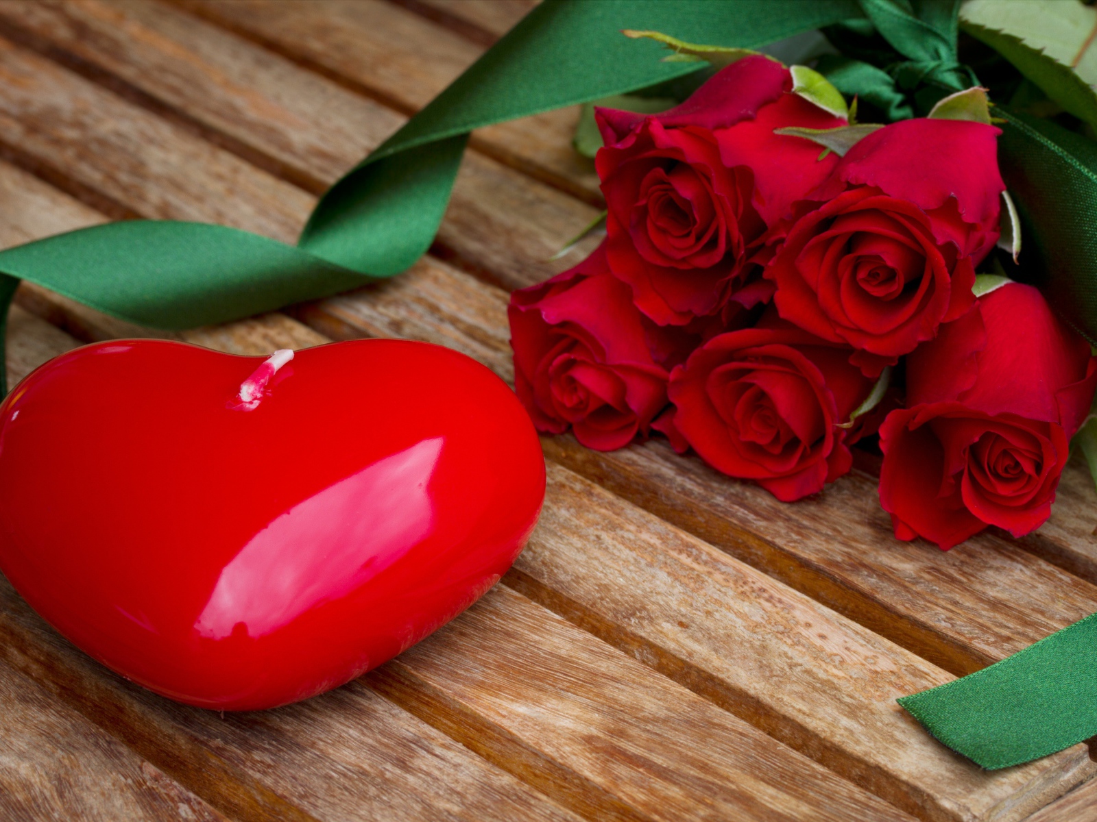 Большое сердце на деревянном столе с букетом красных роз 