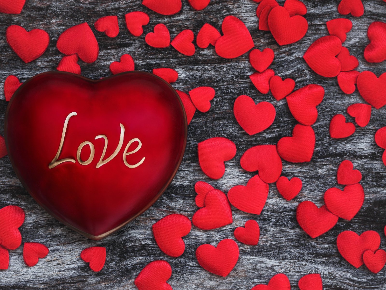 Большое красное сердце на деревянном фоне с маленькими сердечками