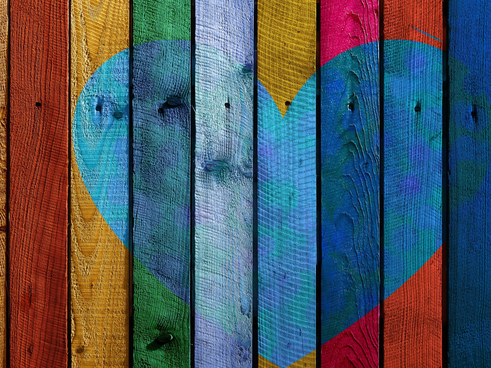 Голубое сердце нарисовано на разноцветном заборе