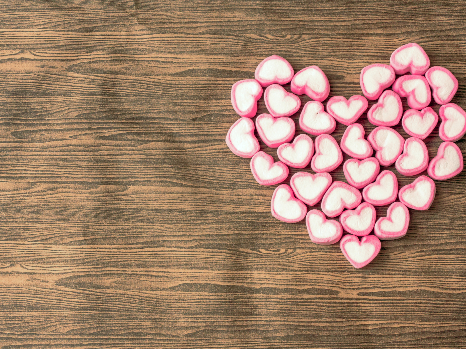 Сердце из конфет на деревянном столе