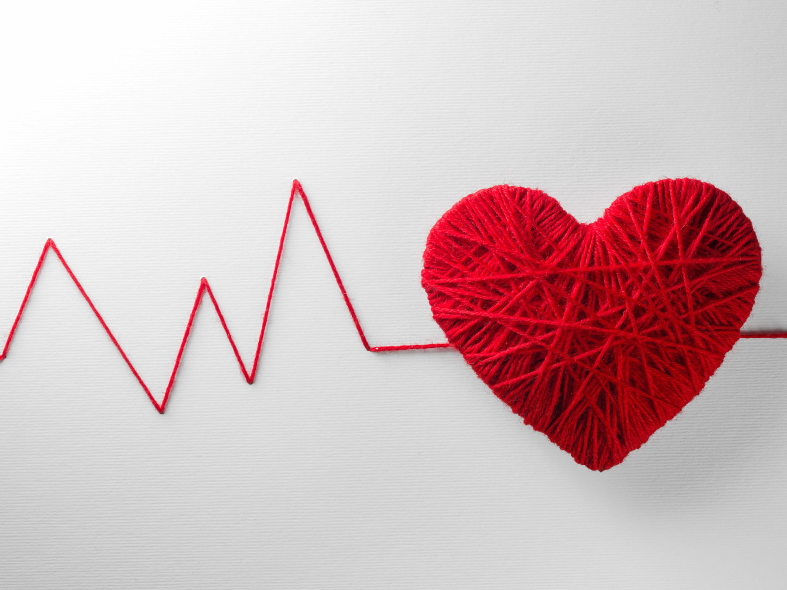 Красное сердце из нитей на сером фоне 