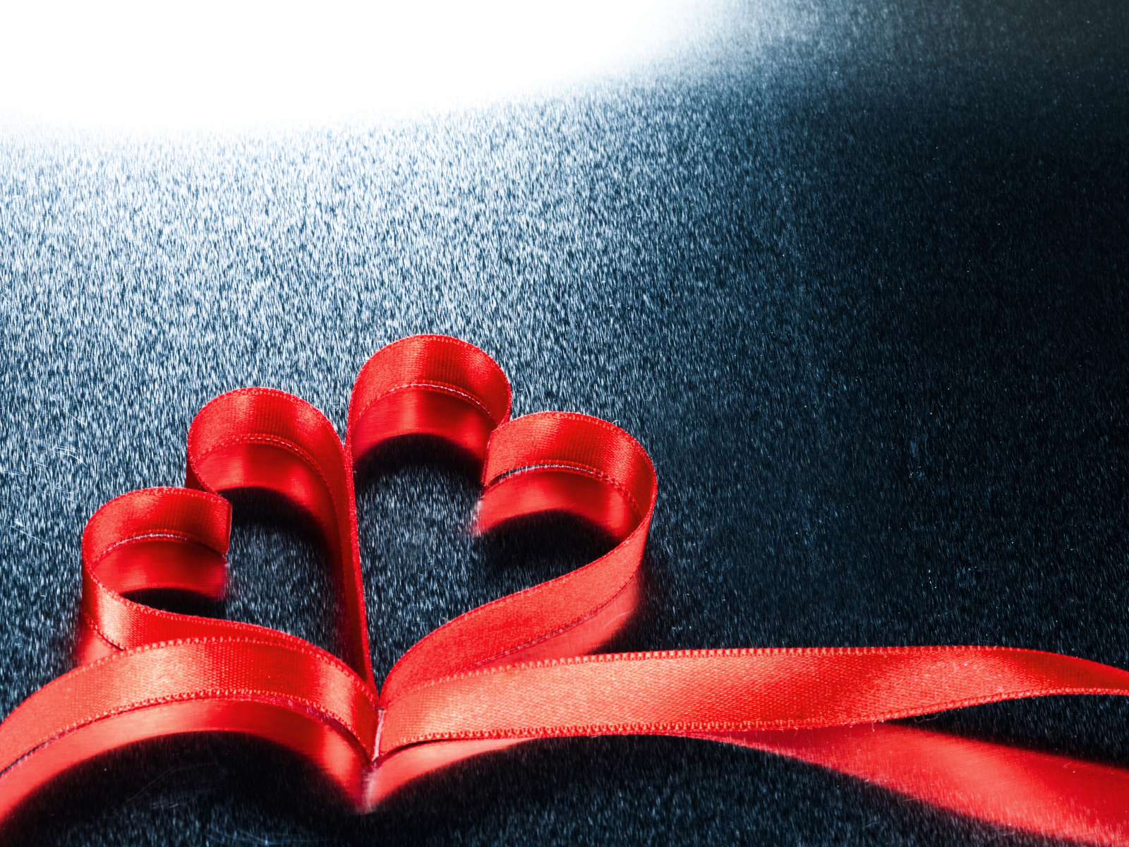 Два красных сердца из ленты на сером фоне 