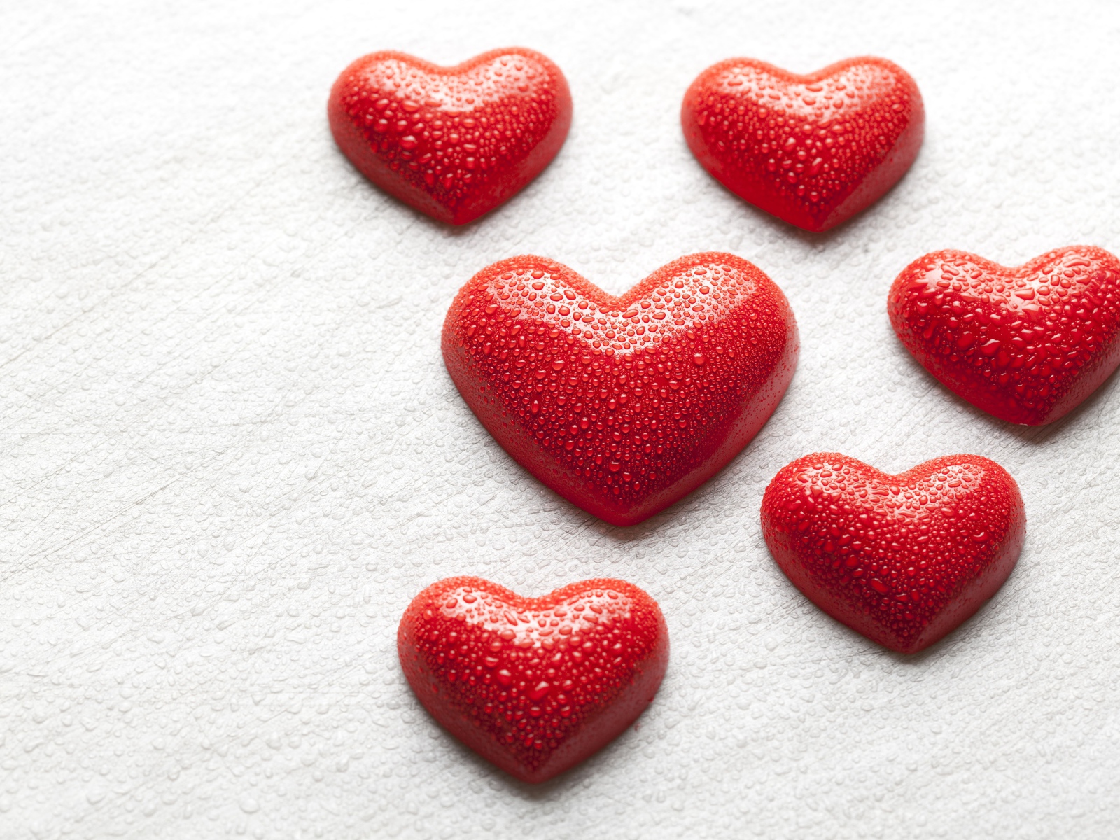 Мокрые красные сердечки на белой поверхности 