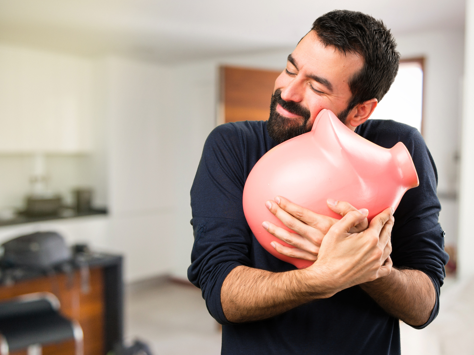 Мужчина обнимает розовую свинью копилку 