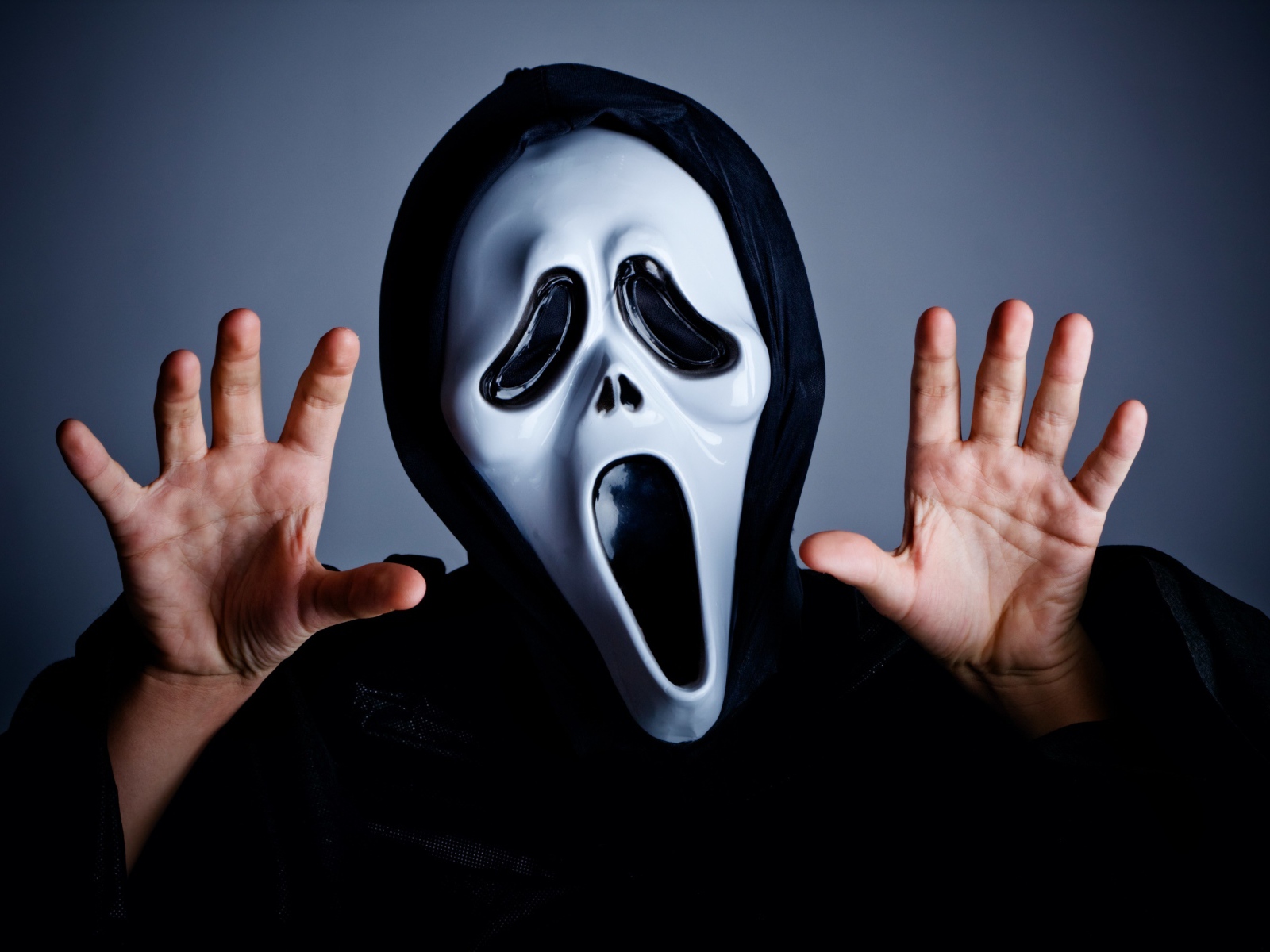 Мужчина в маске пугает на сером фоне