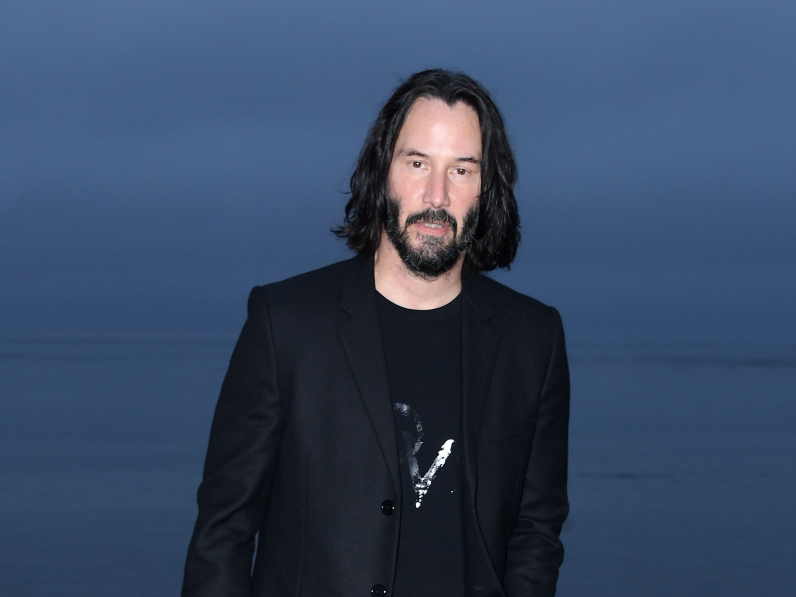 Актер Киану Ривз с бородой на синем фоне