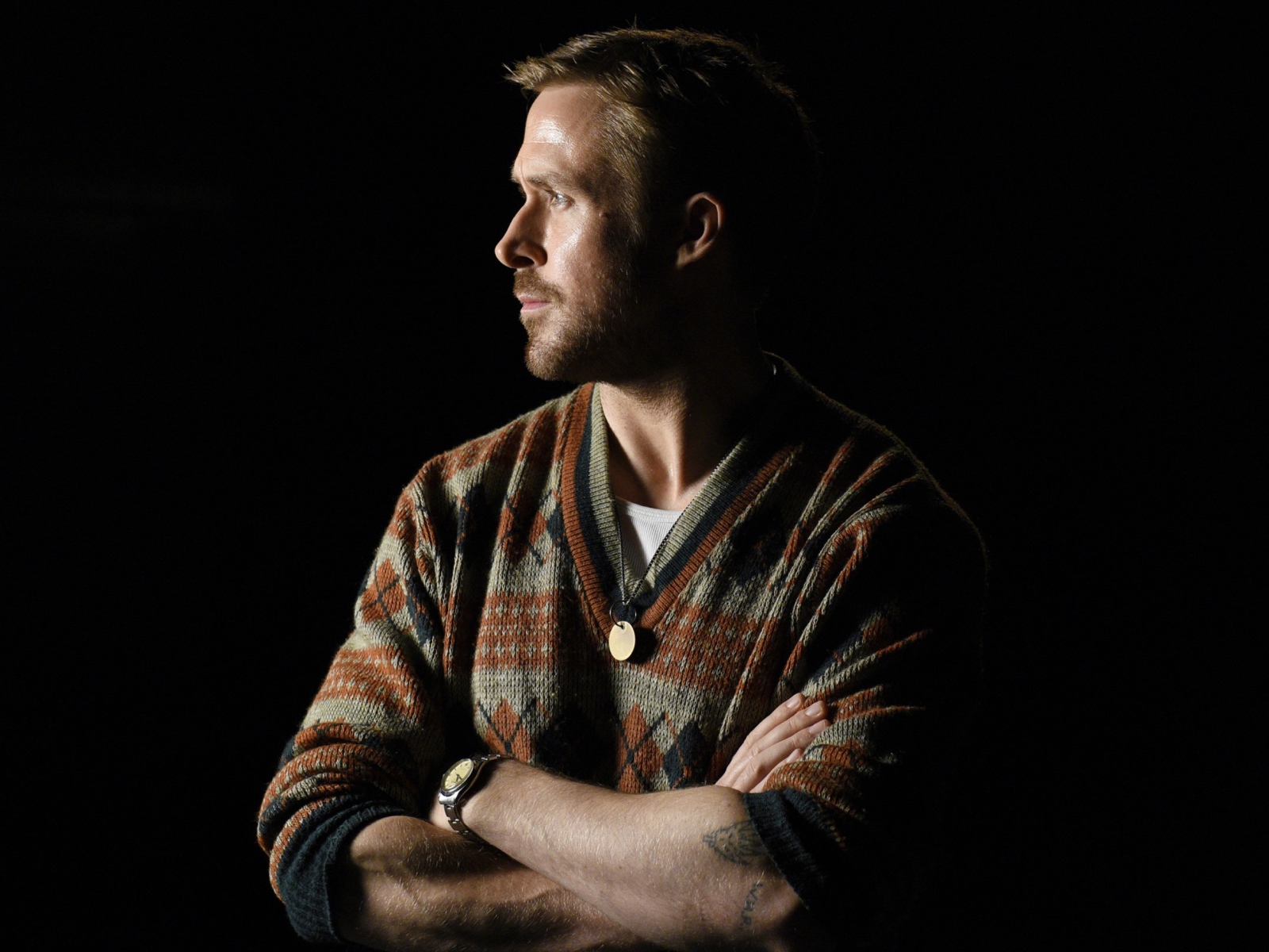 Актер Райан Гослинг в свитере на черном фоне 