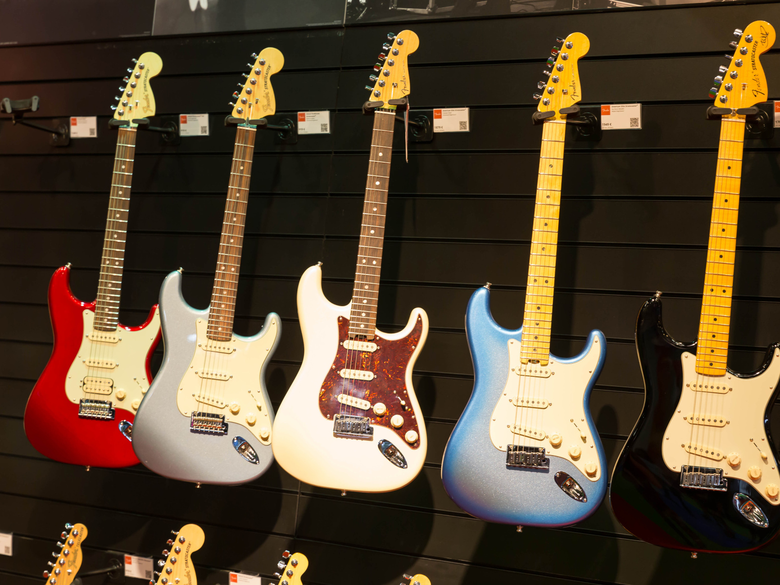 Много разноцветных электрогитар на стене 